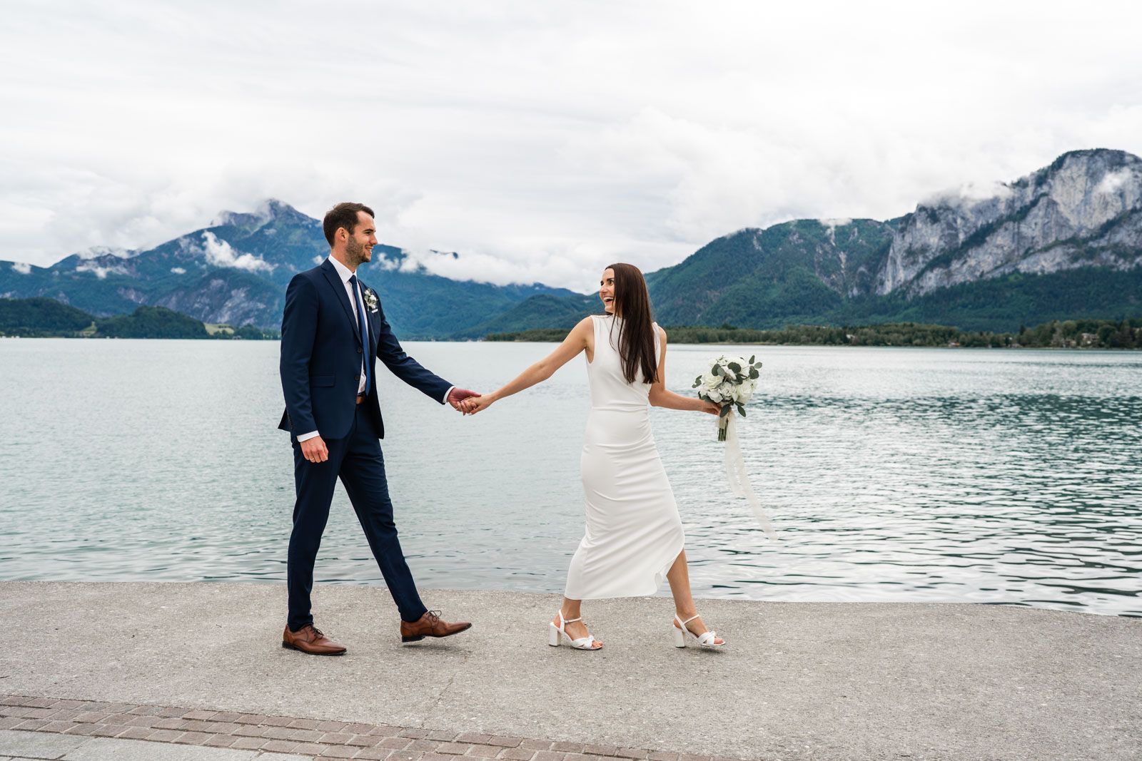 Brautpaar spaziert beim Brautpaarshooting entlang der Promenade am Mondsee. Brautpaar spaziert beim Brautpaarshooting entlang der Promenade am Mondsee.