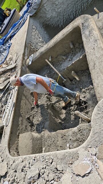 Crew member working on a concrete spa shell and bench