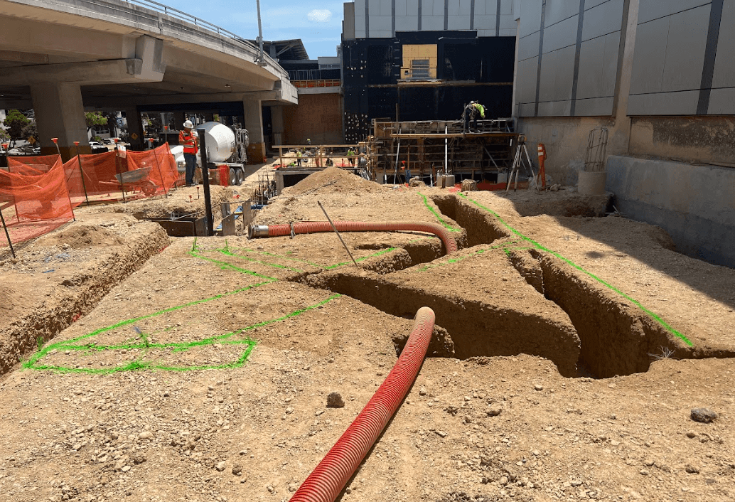 “Active trench excavation with underground utility locating markings and utility coordination at a commercial construction site