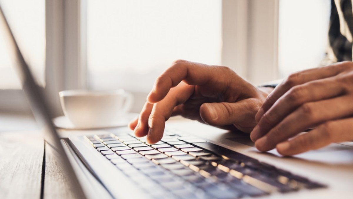 Hands typing a password on a laptop keyboard, showing browser password saving in use