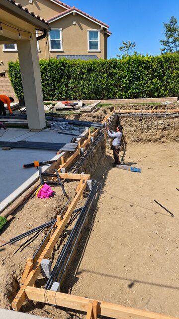 Pool excavation and perimeter reinforcing steel beside a covered patio