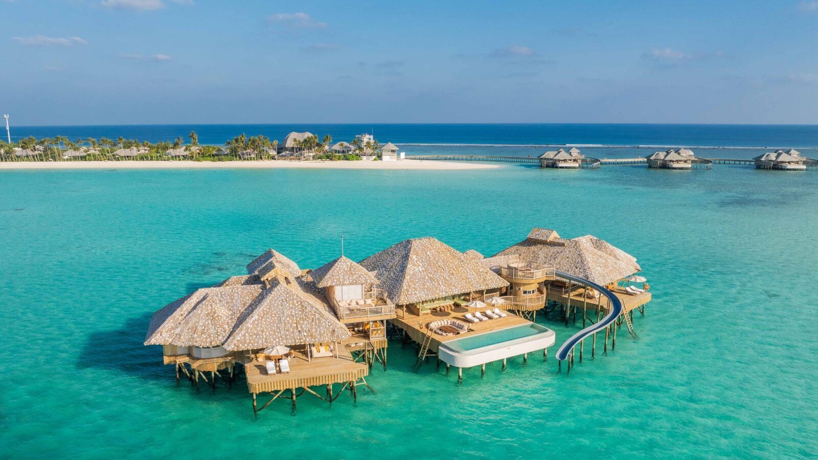 This image shows a large over water villa with pool, water slide and terrace with sun beds at Soneva Secret Resort Maldives in the Indian Ocean.