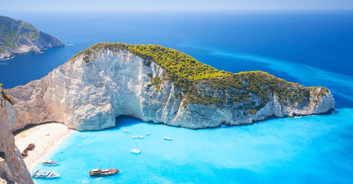 A breathtaking view of Navagio Beach in Zakynthos, Greece, featuring brilliant turquoise water, towering white limestone cliffs, and the famous shipwreck resting on a secluded sandy beach.