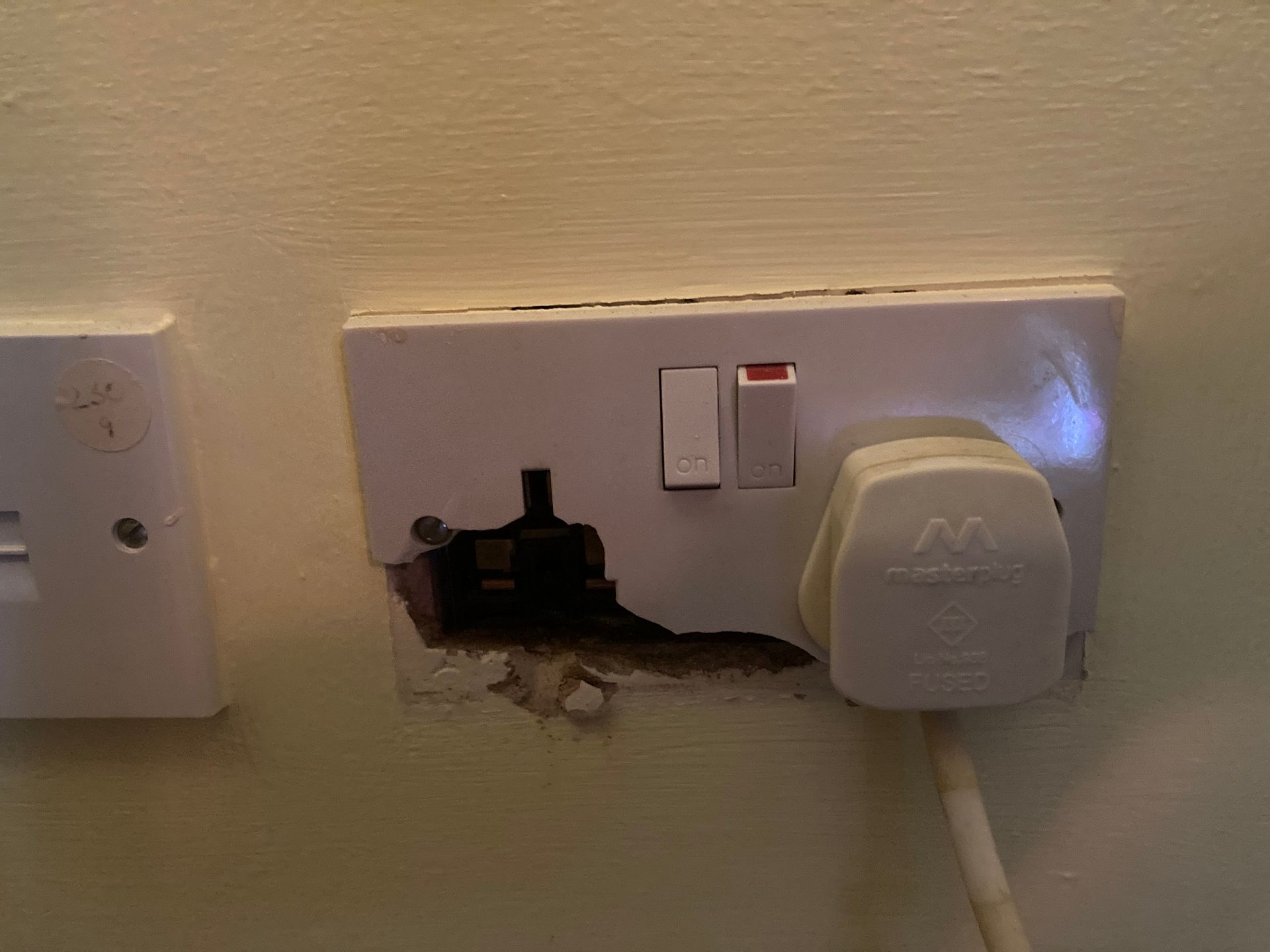 Close-up of a cracked and damaged electrical socket on a wall in Elm, showing why professional socket replacement is needed. Close-up of a cracked and damaged electrical socket on a wall in Elm, showing why professional socket replacement is needed.
