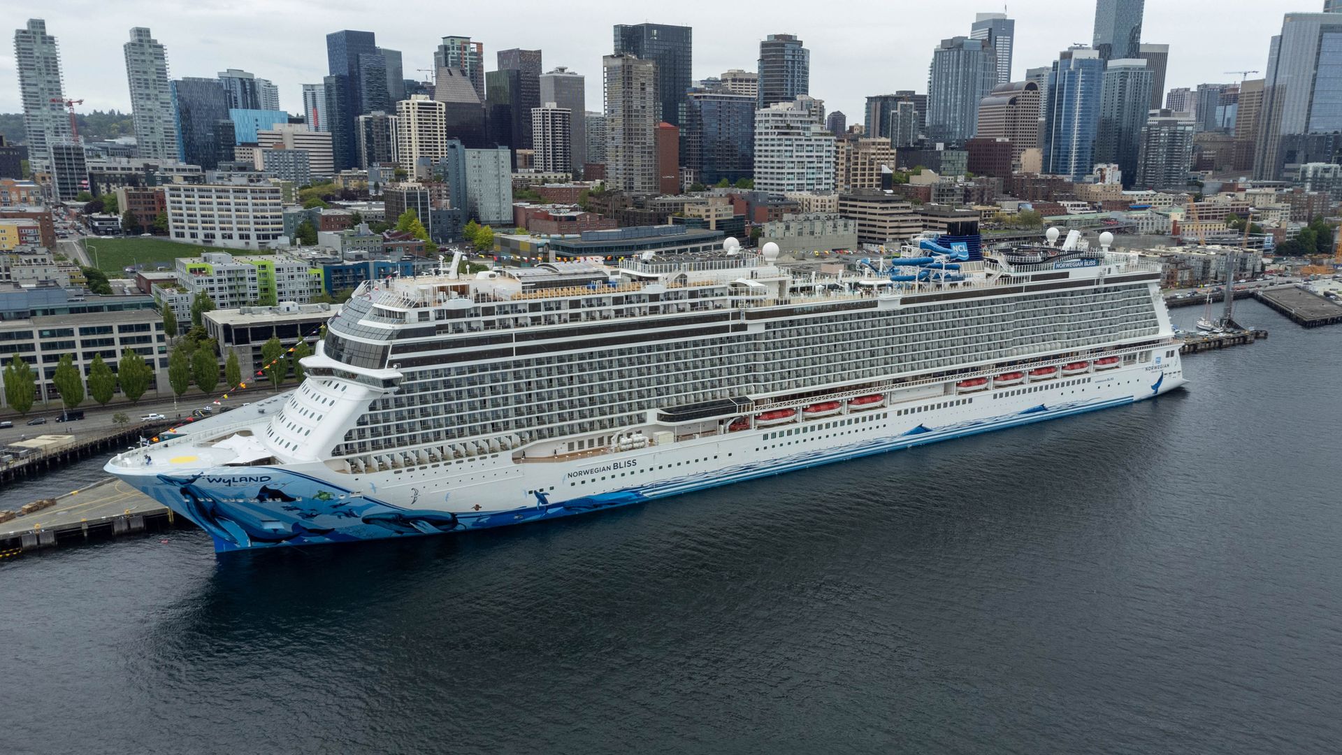 Norwegian Bliss docked along the Seattle waterfront, with the downtown skyline rising behind the ship.