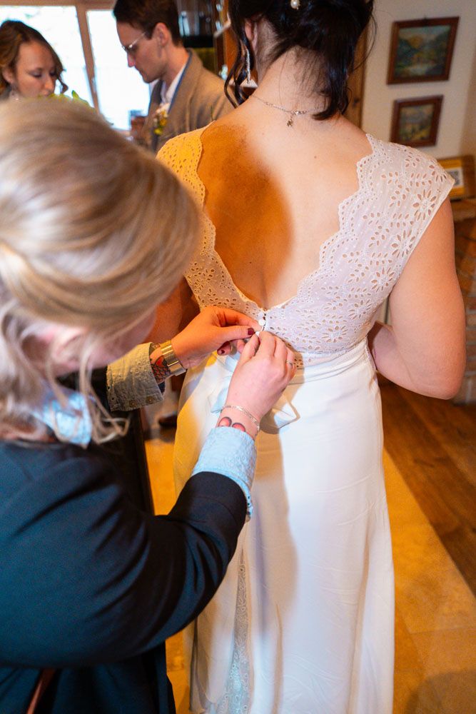 Detailaufnahme beim Getting Ready der Braut beim Schließen des Hochzeitskleids