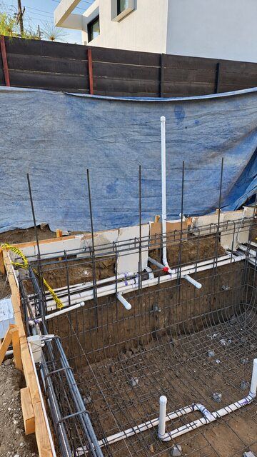 Pool shell reinforcing steel with installed plumbing lines