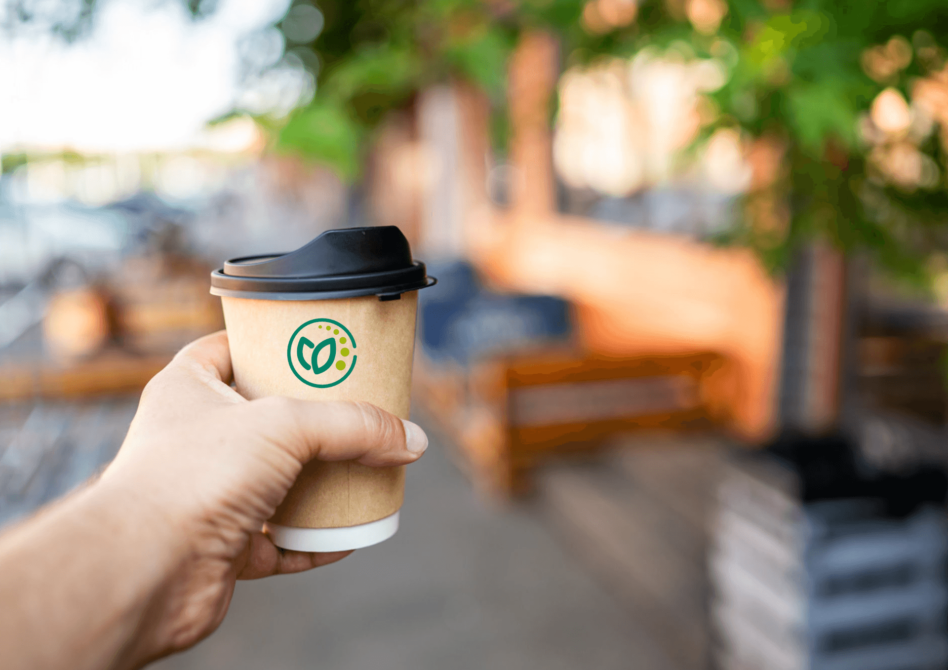 hand holding paper coffee cup with a black lid, set against a blurred background of green foliage and warm sunlight. Ideal for themes of outdoor relaxation, coffee culture, and eco-friendly lifestyle. hand holding paper coffee cup with a black lid, set against a blurred background of green foliage and warm sunlight. Ideal for themes of outdoor relaxation, coffee culture, and eco-friendly lifestyle.