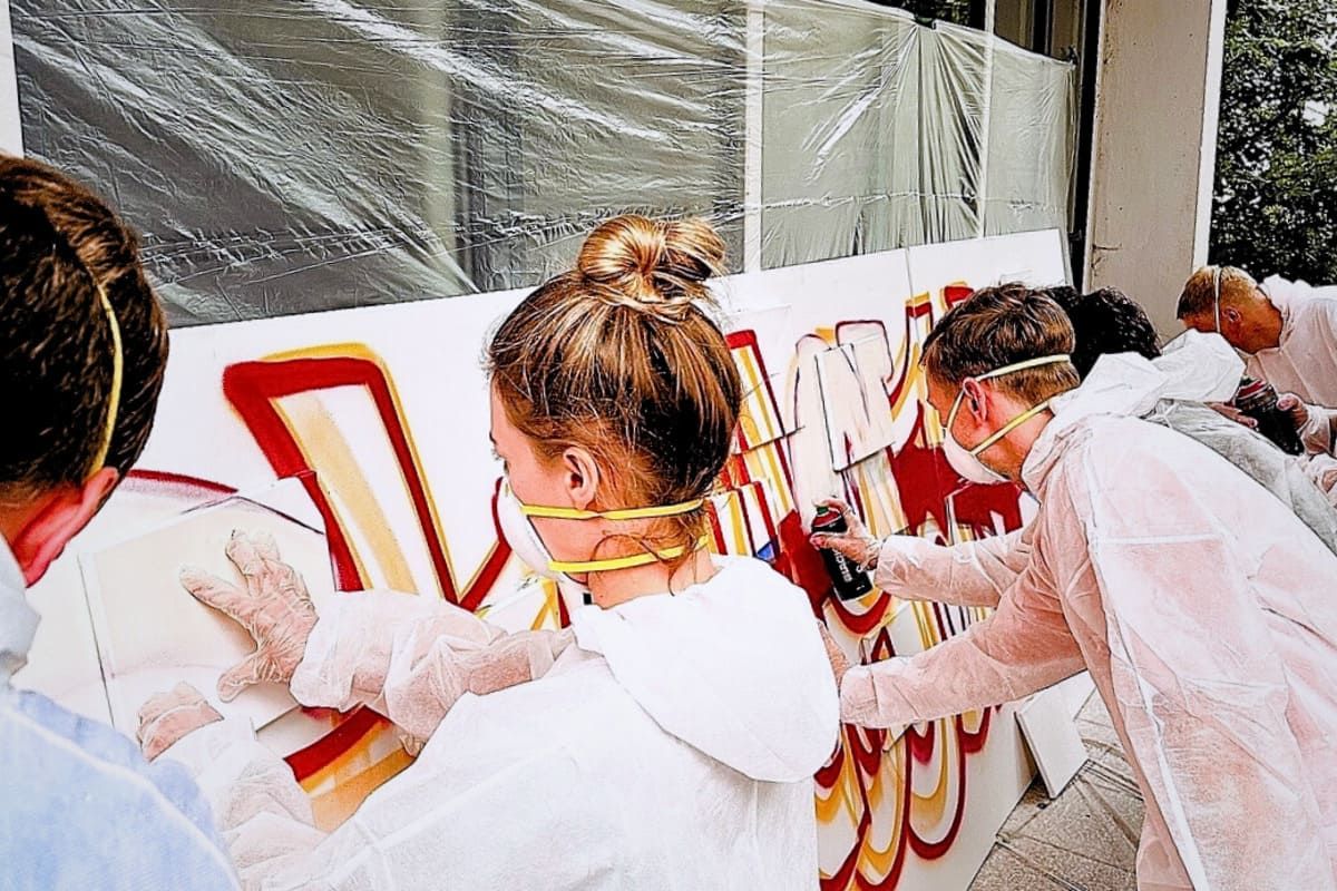 Teilnehmende beim Graffiti Workshop Stuttgart mit dem VfB beim gemeinsamen Sprayen im Jugendhaus Mitte