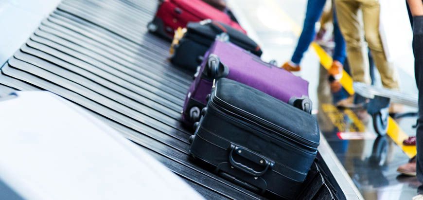 Checked suitcases arriving on an airport baggage carousel.
