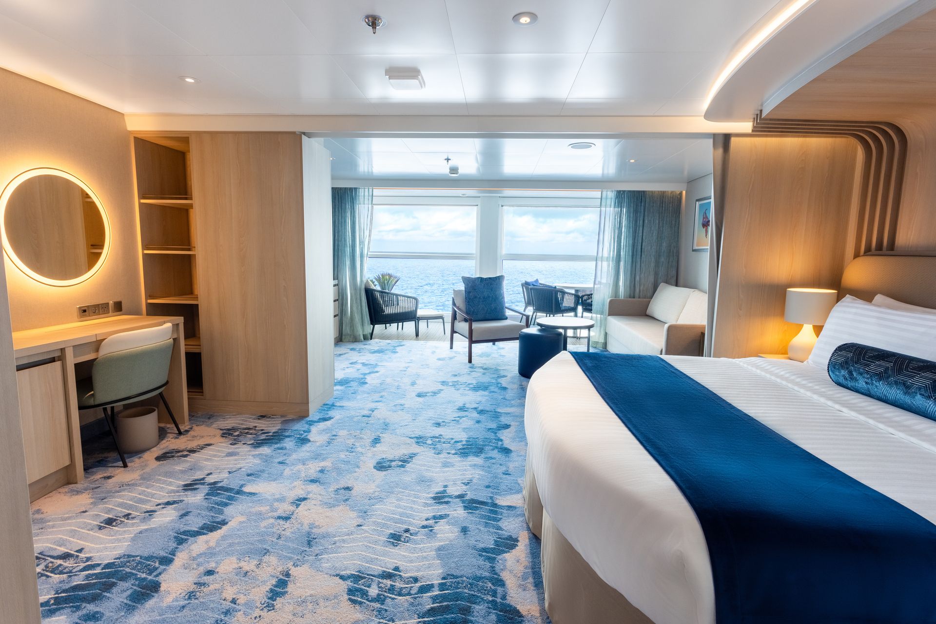 Modern cruise ship rooms with large windows, ocean scenery, and cozy seating areas.