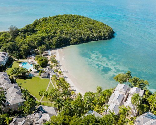 Aerial view of Couples Sans Souci in Jamaica with a private beach, lush green hillside, and calm turquoise Caribbean waters.