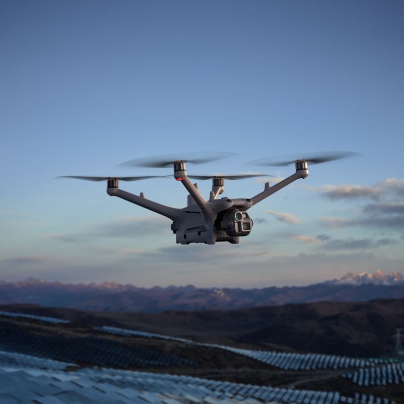 DJI Matrice 4TD enterprise drone top view showing gray body, orange accents, triple-camera gimbal with thermal and telephoto sensors