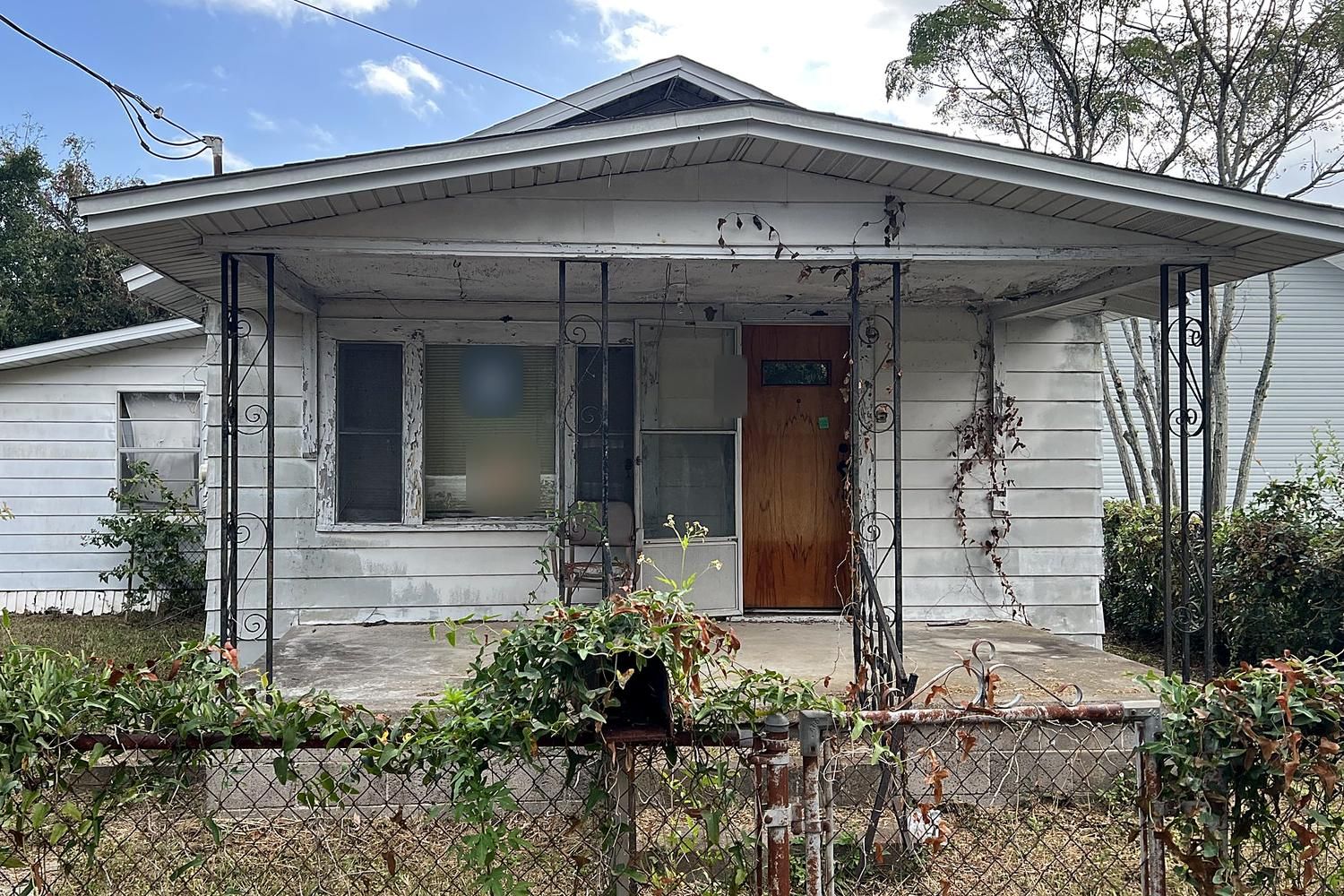 The same cottage before renovation, with peeling siding and an overgrown yard