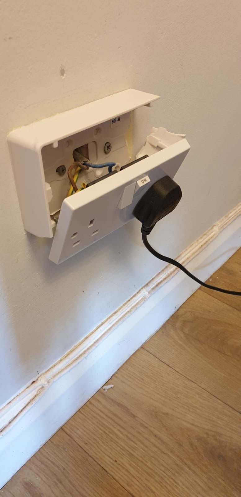 Broken and loose electrical wall socket with visible wear and damage, photographed before replacement in the Fenlands Broken and loose electrical wall socket with visible wear and damage, photographed before replacement in the Fenlands