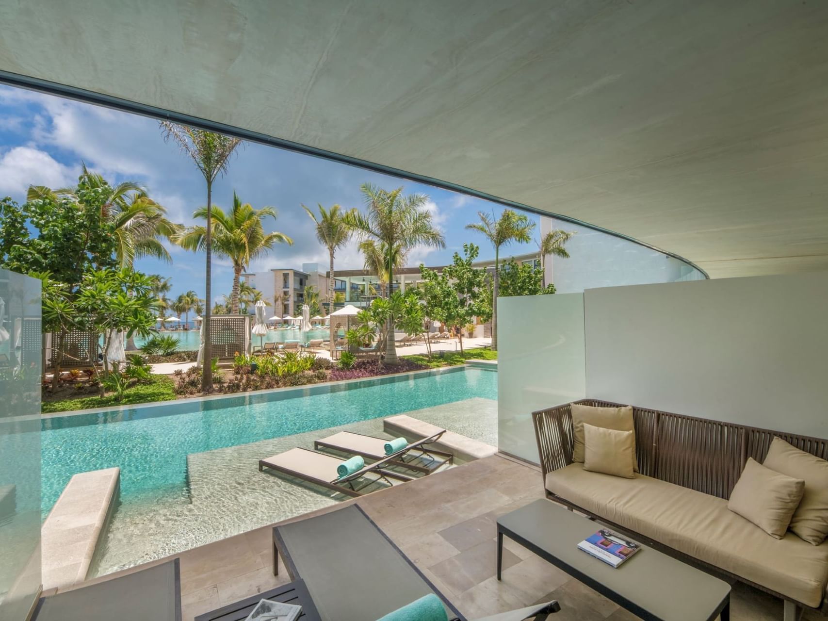 Romantic swim-out suite at Haven Riviera Cancun featuring private loungers, a shaded terrace, and direct access to a serene pool with tropical garden views. 