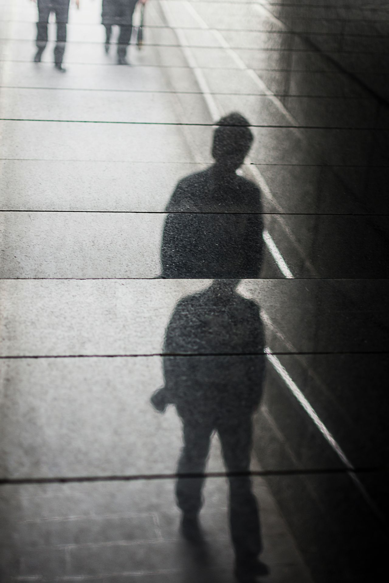 Shadow of a person walking down a sidewalk, symbolizing the persistent and haunting presence of burnout and clinical depression since middle school.