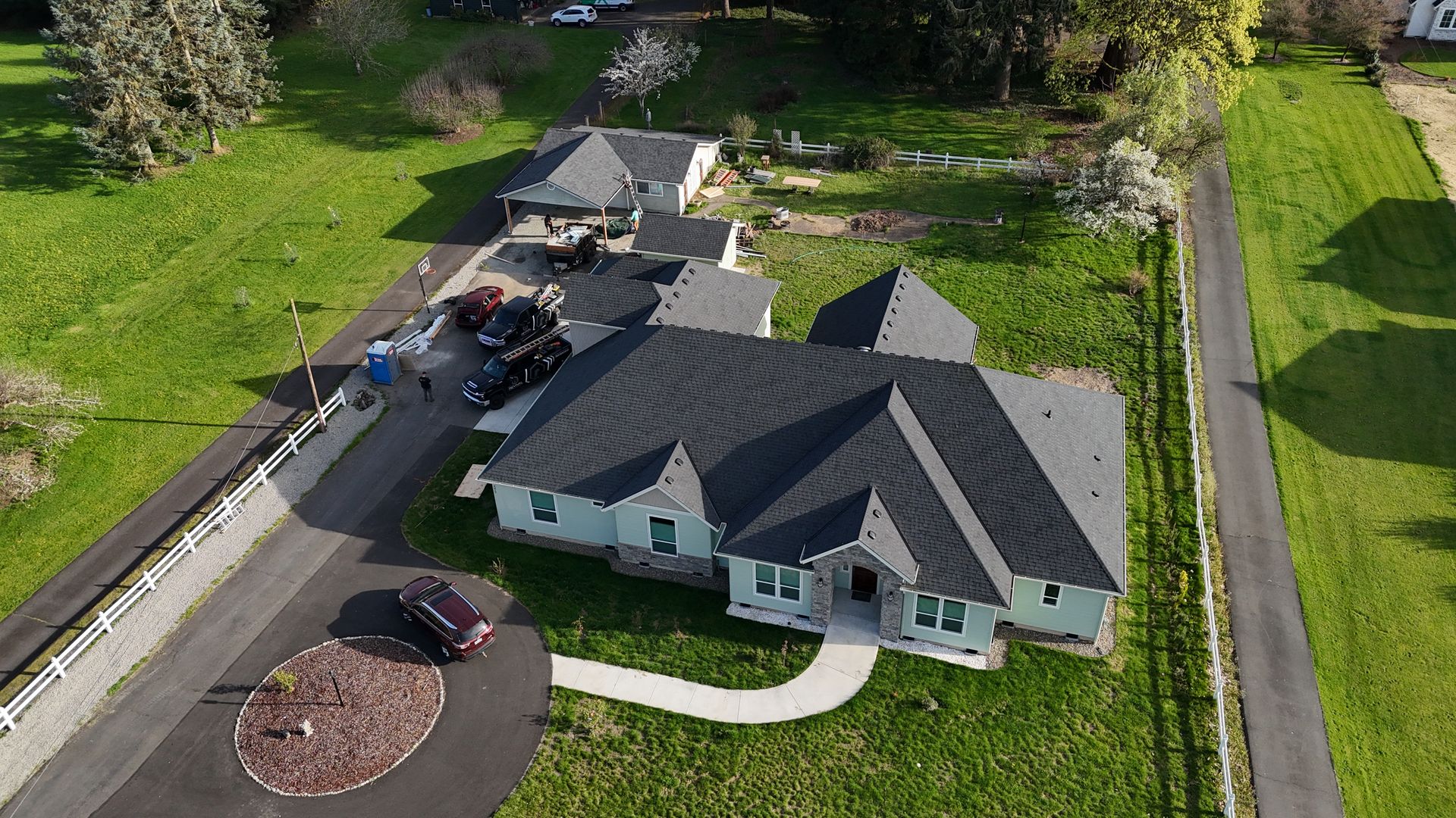 Aerial view of a house with a shingle roof and surrounding lawn. Aerial view of a house with a shingle roof and surrounding lawn.