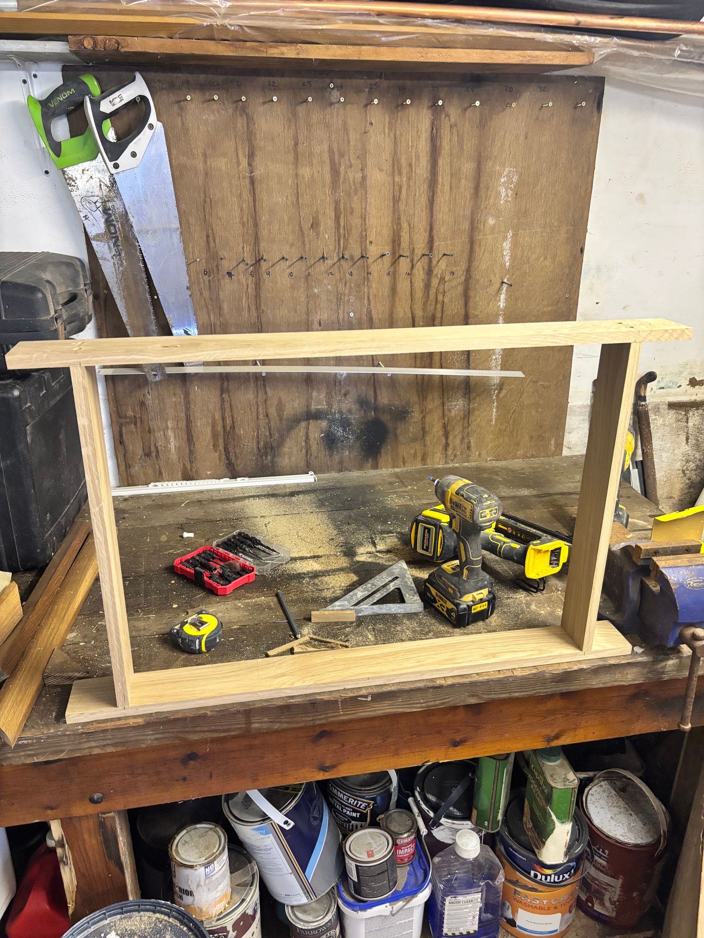 Oak mirror frame being built in the workshop, with tools and saws visible on the workbench