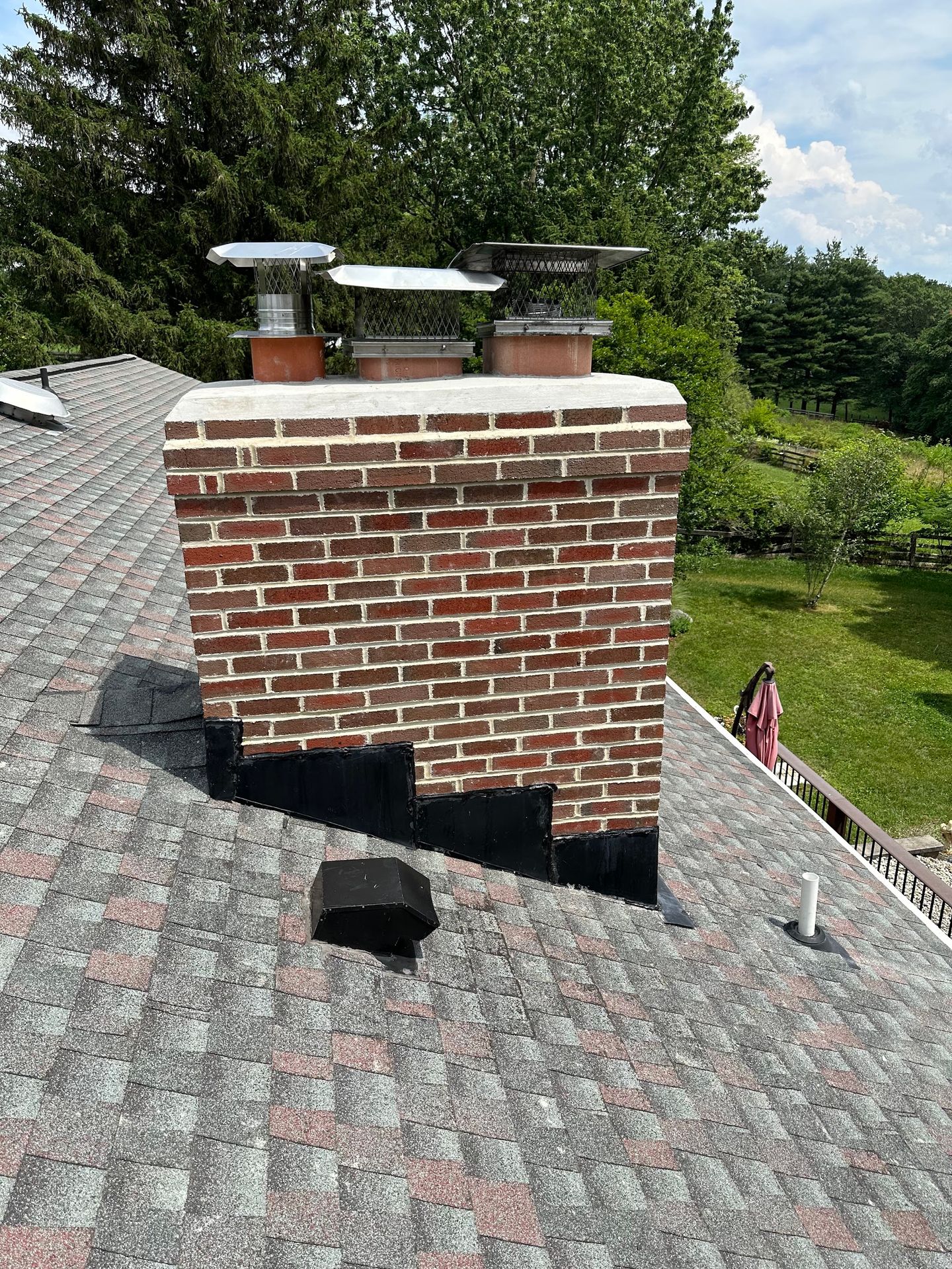 Close-up of technician's gloved hands installing new metal chimney cap on residential brick chimney