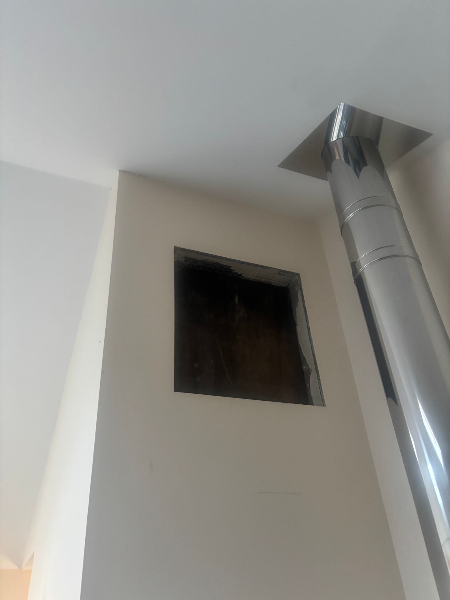 The open wall showing the hole beside the flue before any repairs