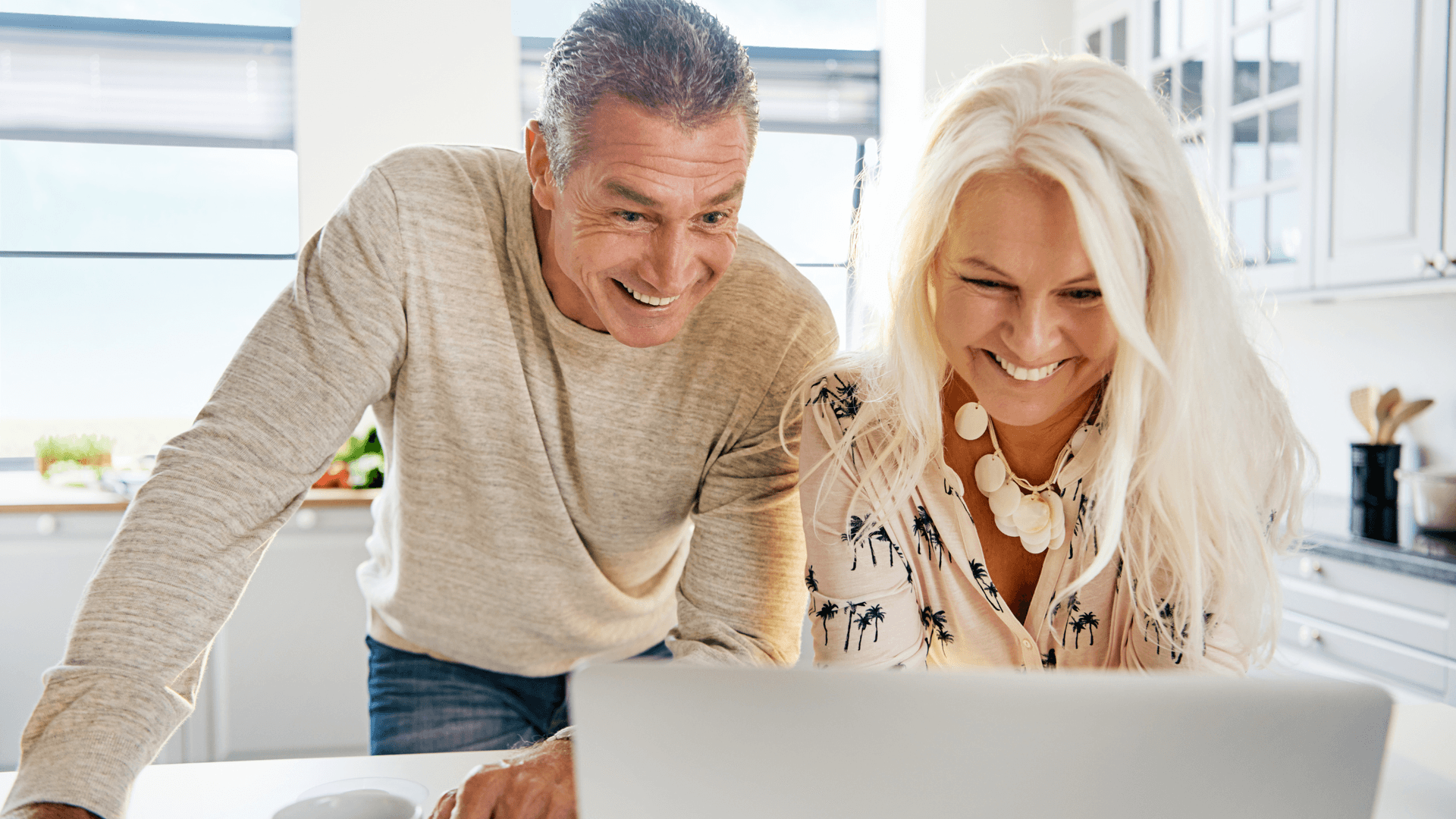 Smiling couple planning a vacation together on a laptop.