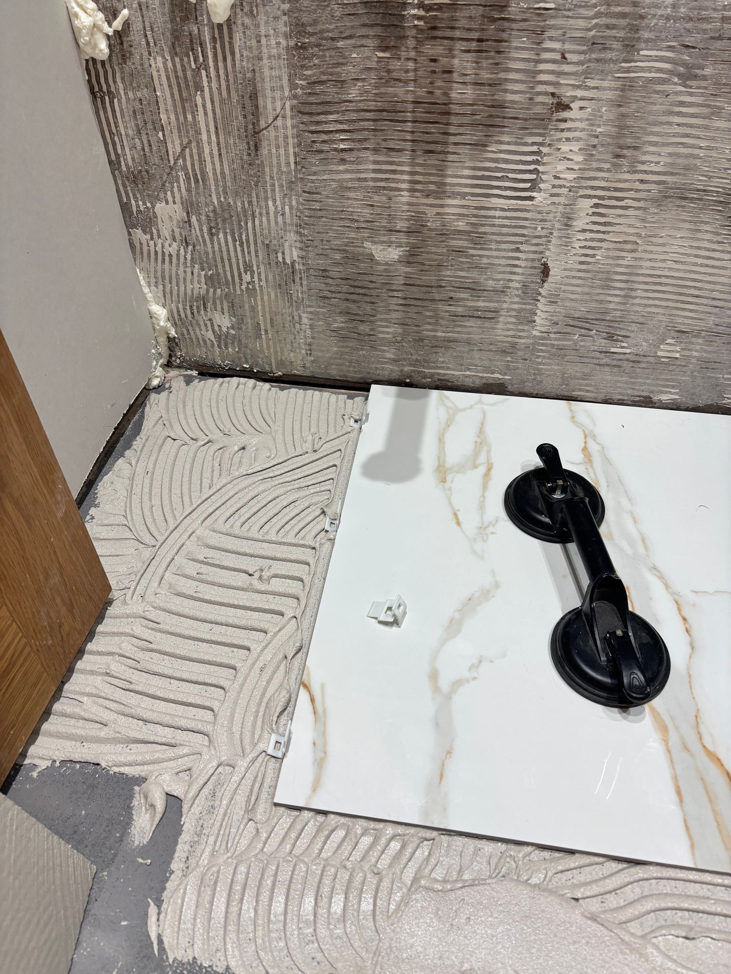 porcelain tiles being fitted during tiling work in a bathroom in Elm. porcelain tiles being fitted during tiling work in a bathroom in Elm.