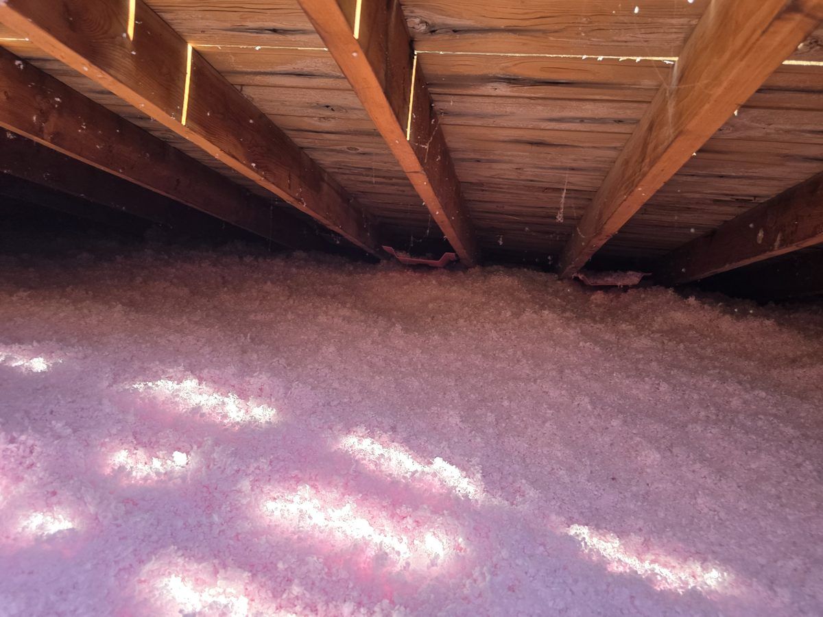 Thick new pink blown-in insulation across an attic floor