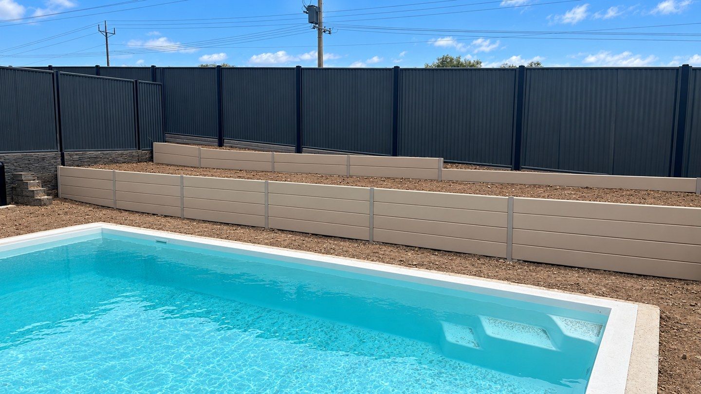 Poolside concrete sleeper wall with bare soil