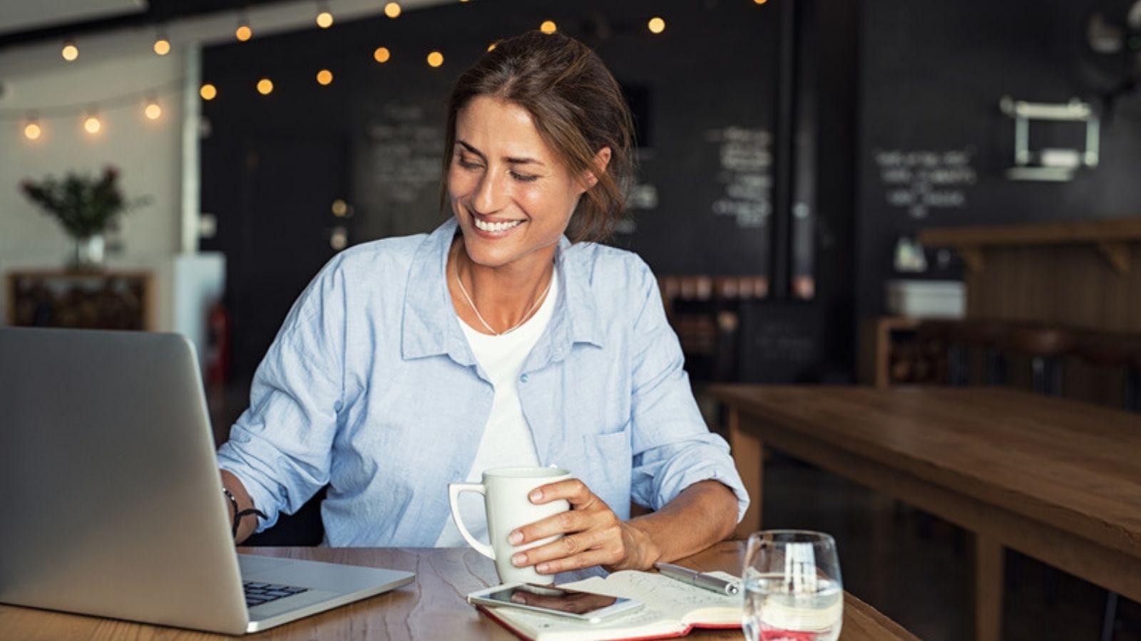 Woman using a laptop in a coffee shop on public Wi-Fi, The Public Wi-Fi Habit I Finally Broke