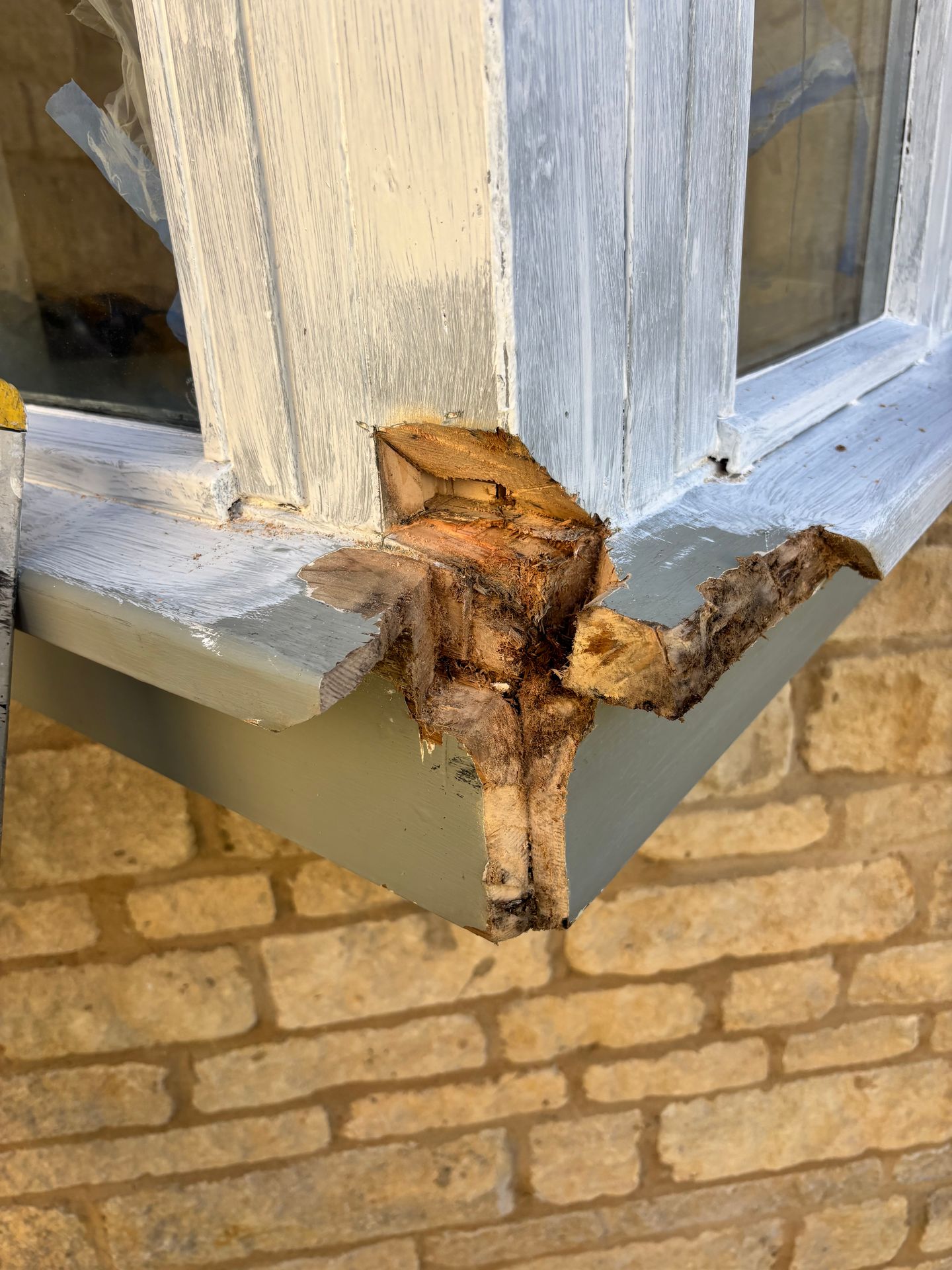 Rotten corner of exterior timber window showing exposed, decayed wood.