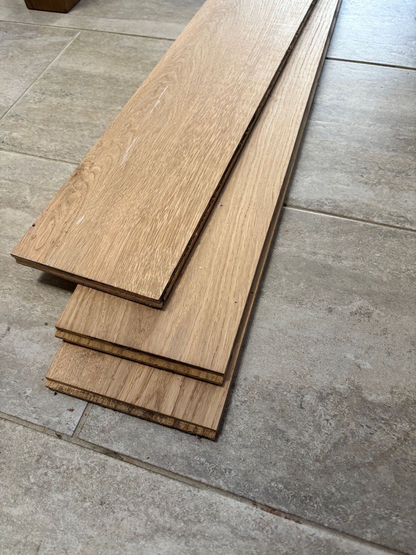 Three oak boards laid out on a tiled floor, ready to be crafted into a bespoke mirror.
