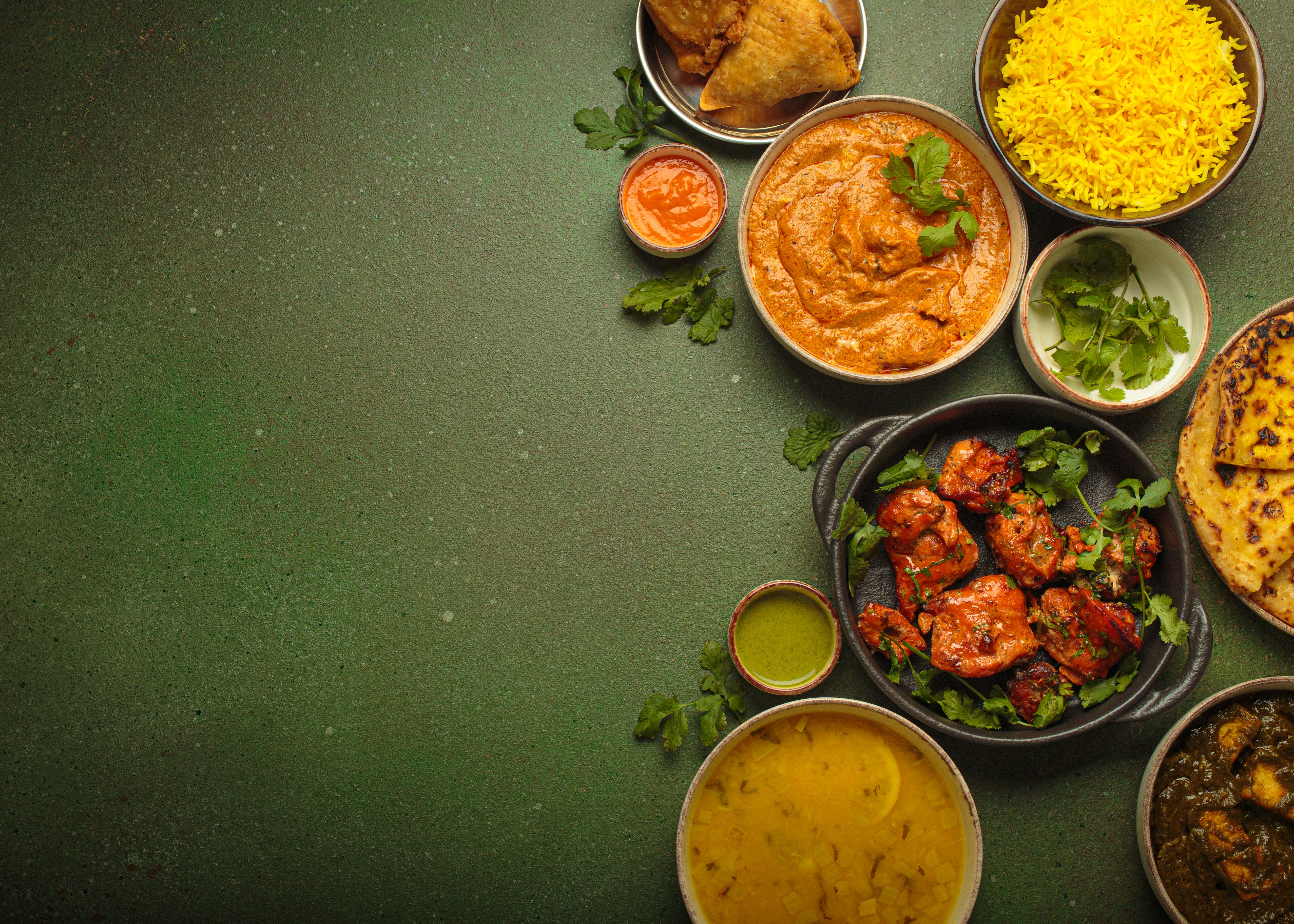 Traditional assorted Indian dishes arranged top view on green background table. Cuisine of India, space for text Traditional assorted Indian dishes arranged top view on green background table. Cuisine of India, space for text