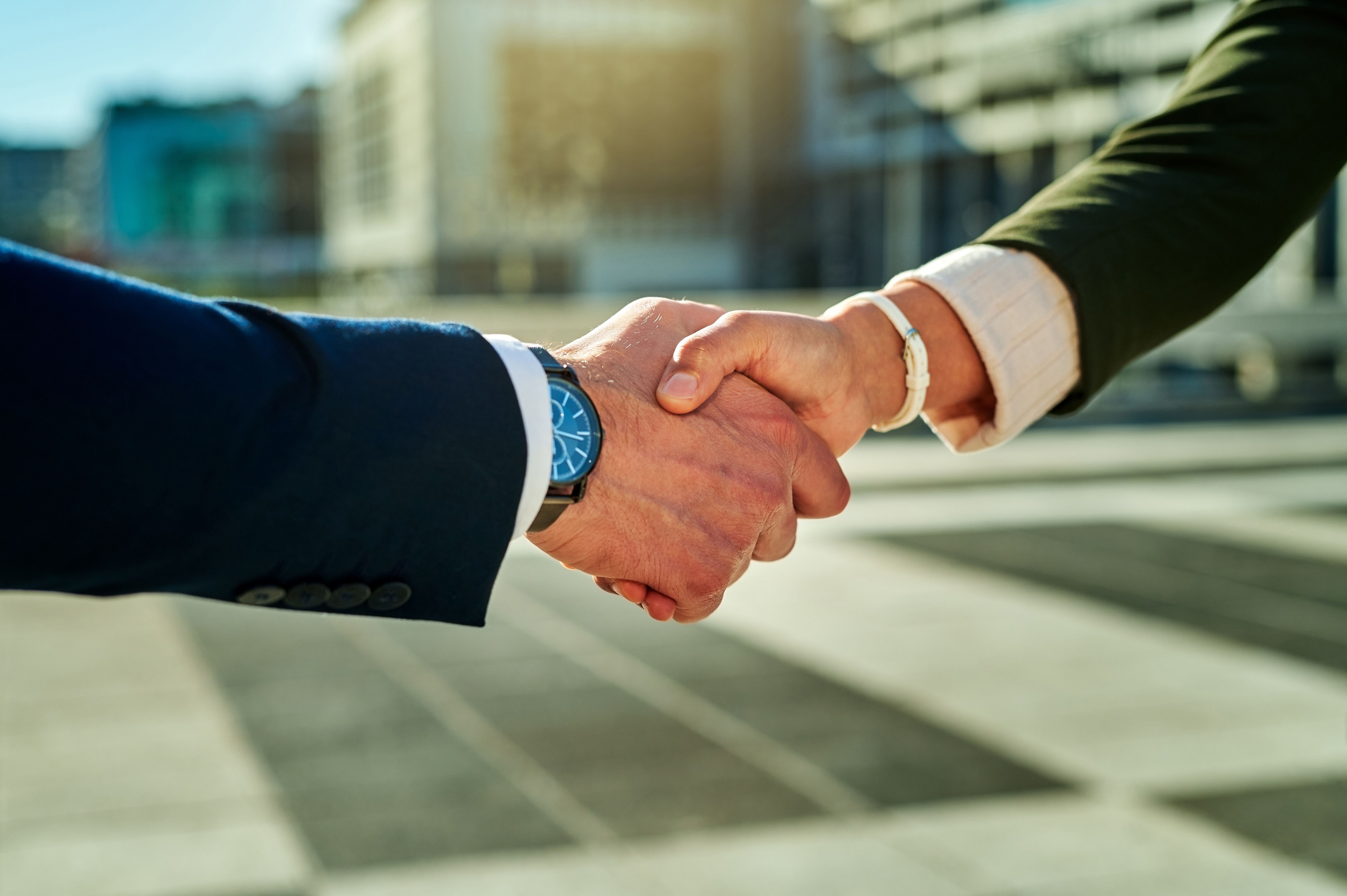 Shot of two businesswomen shaking hands against a city background