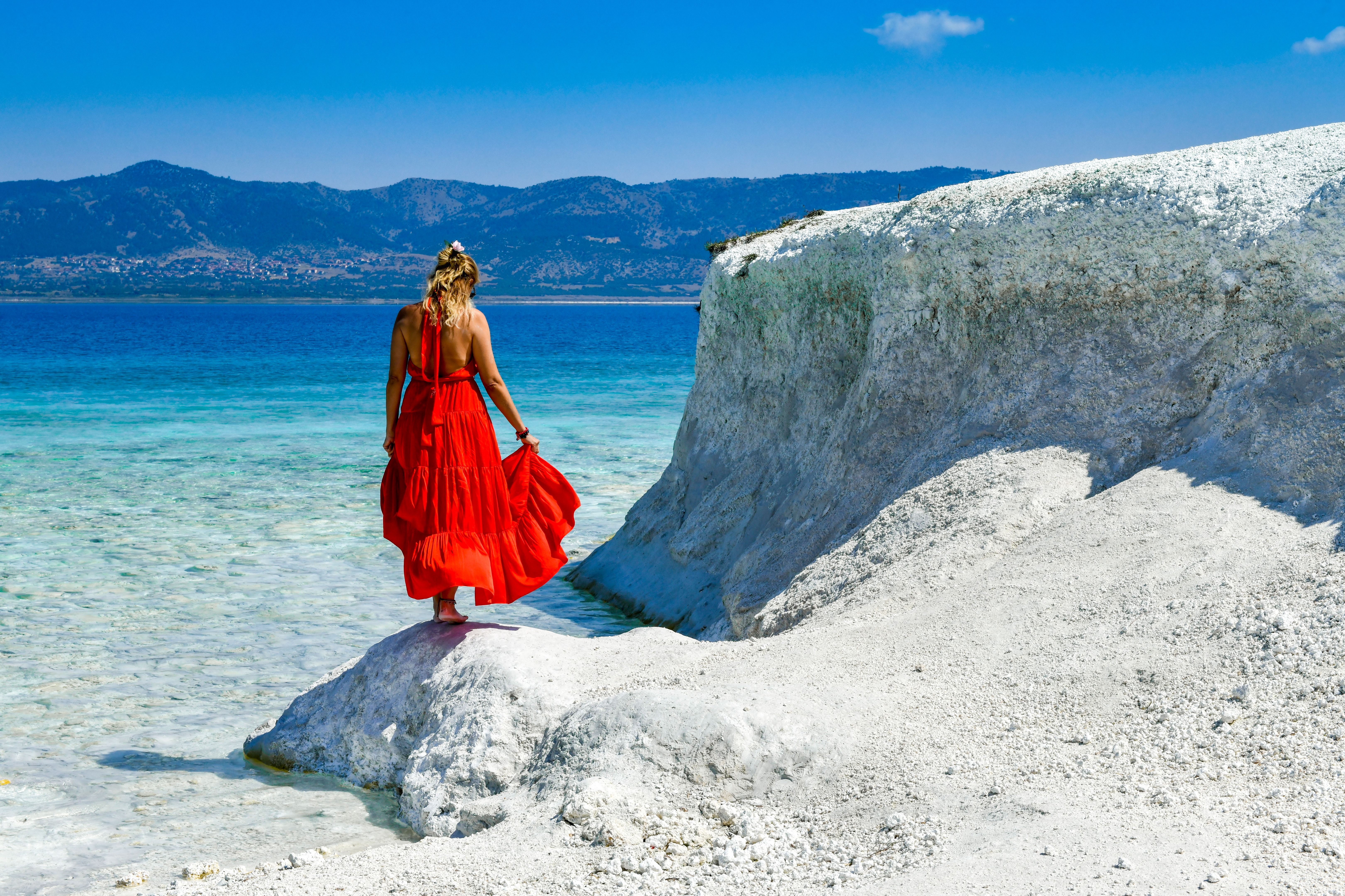 Woman in red dress walking on the beach.