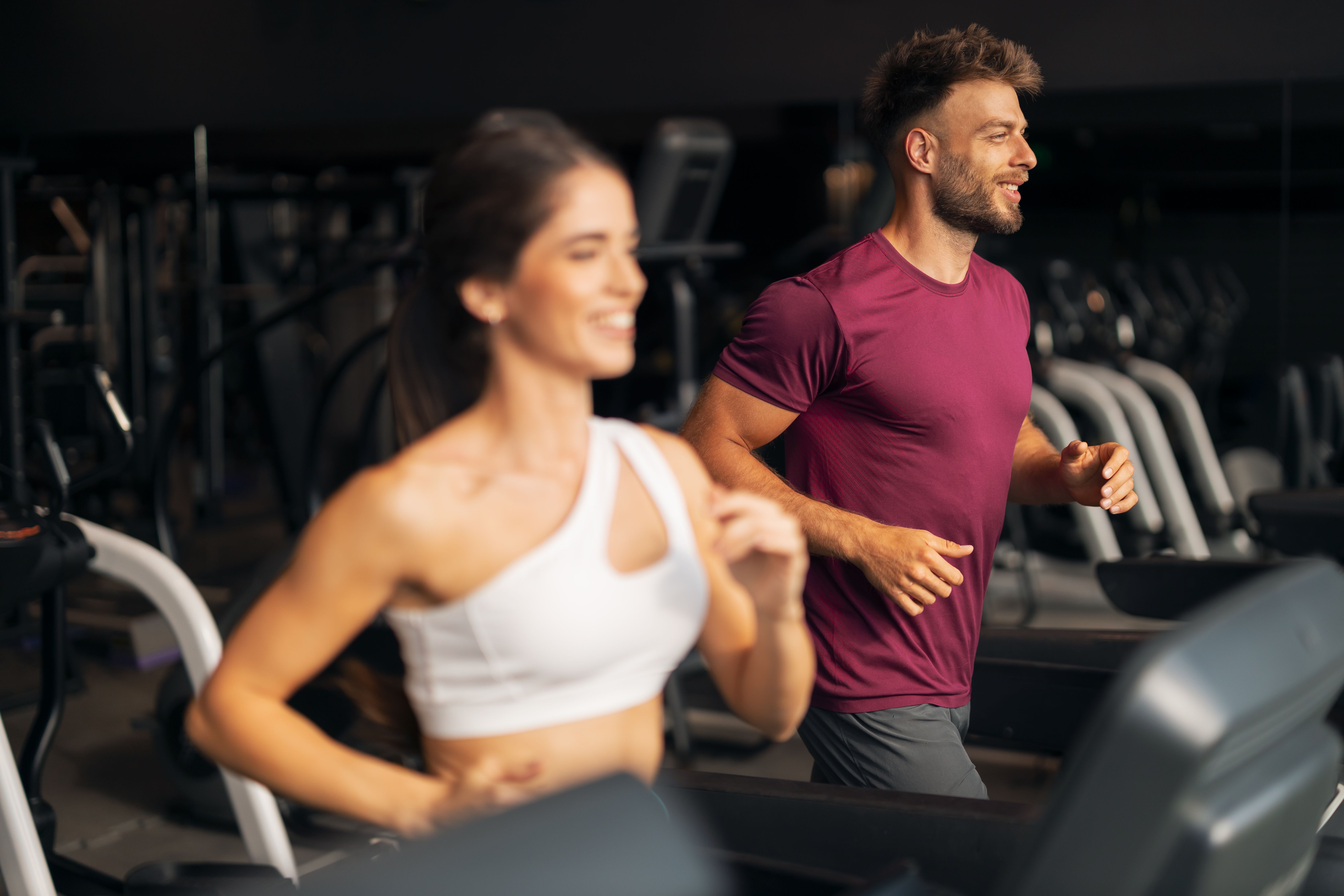 Una pareja de adultos jóvenes en forma corriendo juntos en una cinta de correr Una pareja de adultos jóvenes en forma corriendo juntos en una cinta de correr