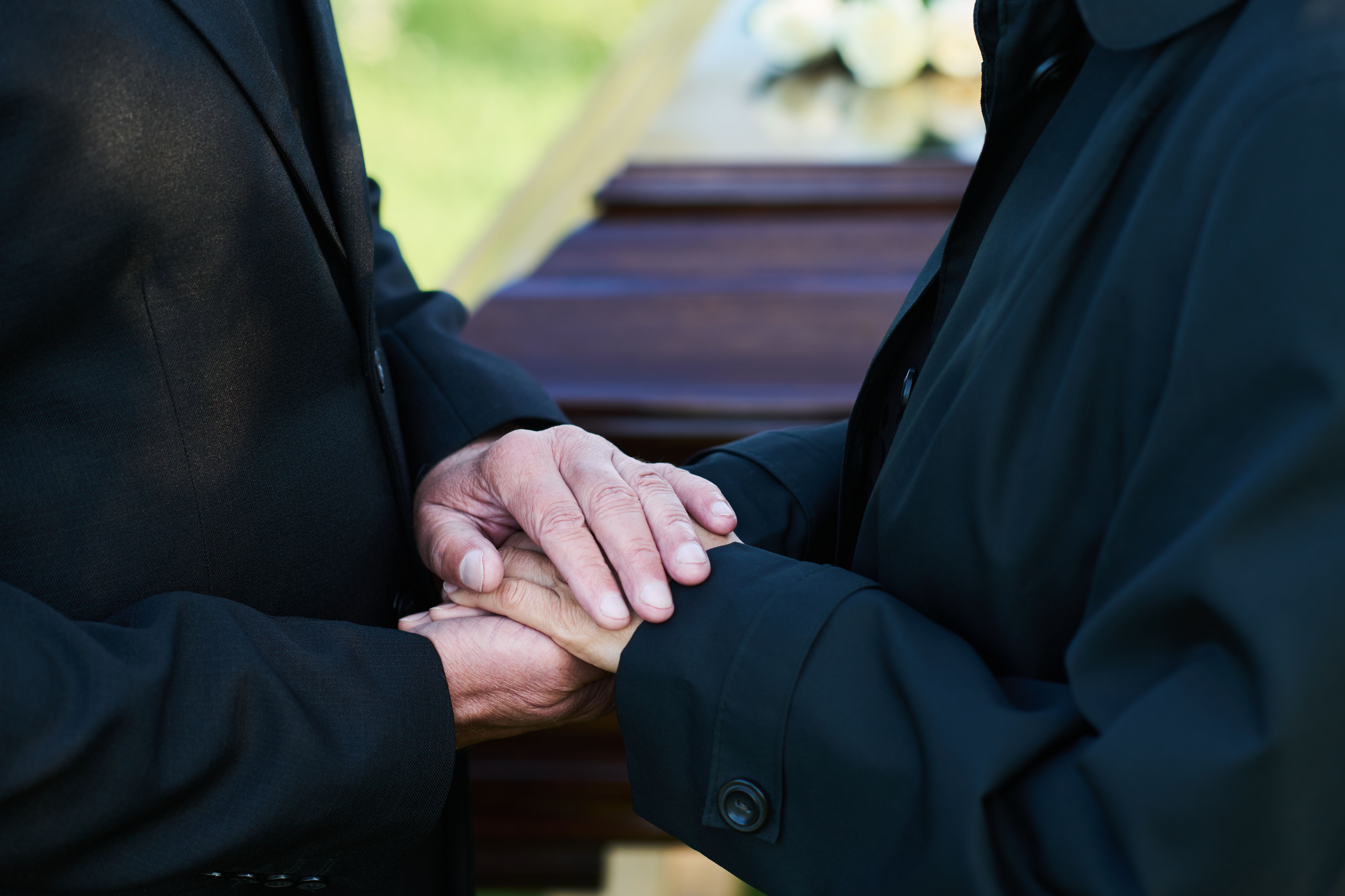 Close-up of hands of mature grieving man on those of his mourning wife Close-up of hands of mature grieving man on those of his mourning wife