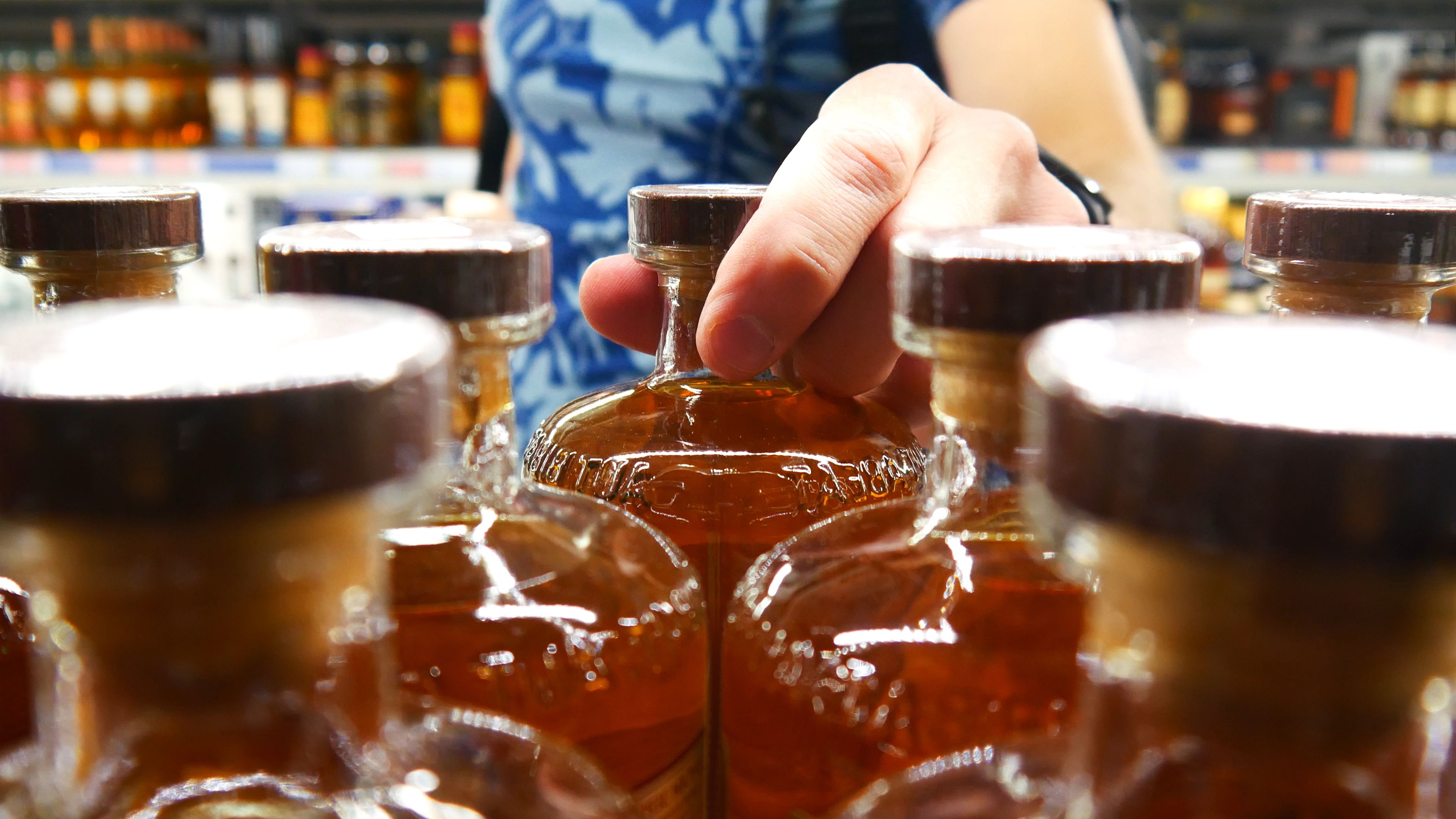 A male buyer taking a whiskey bottle in alcohol store