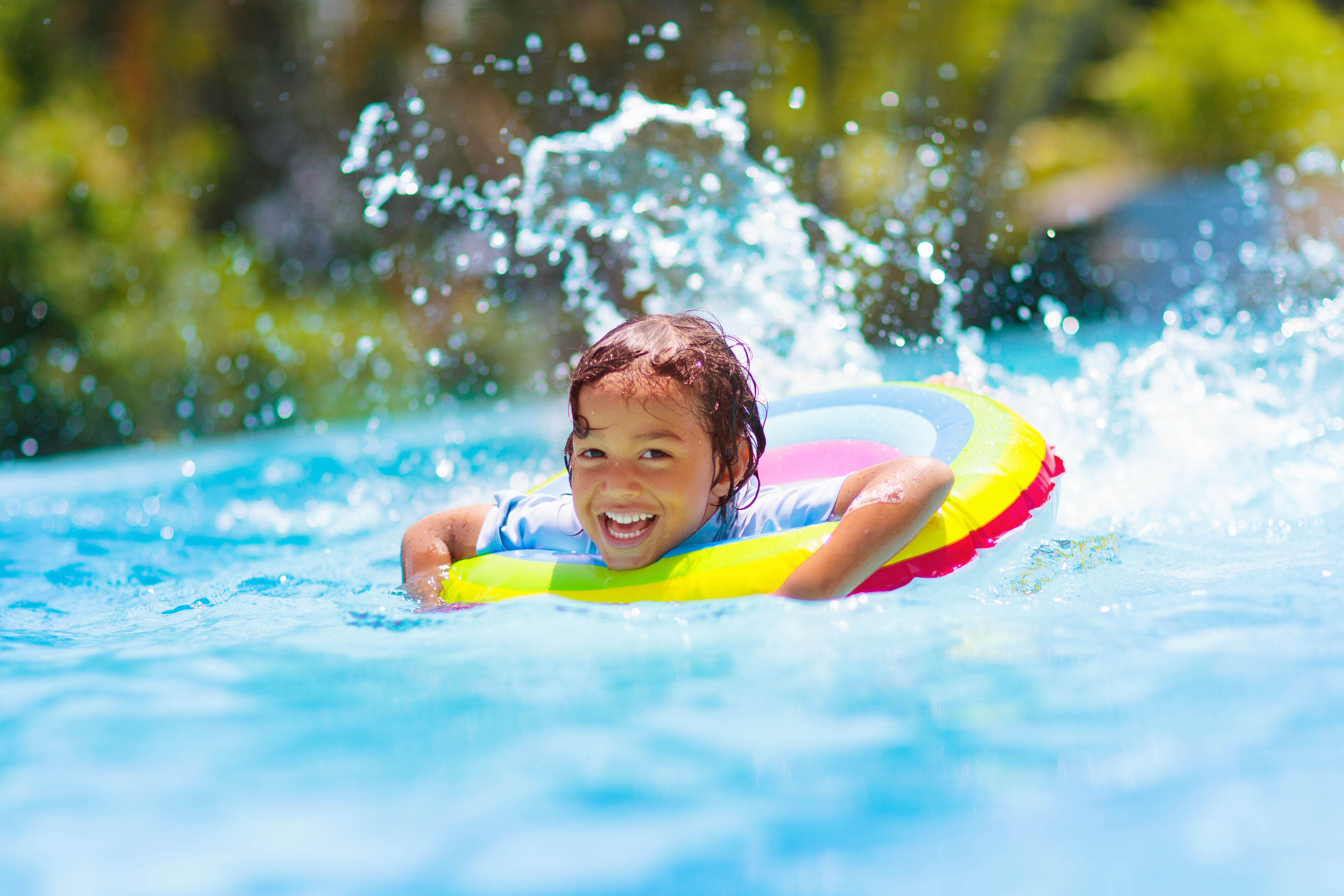 Child in swimming pool on toy ring. Kids swim.