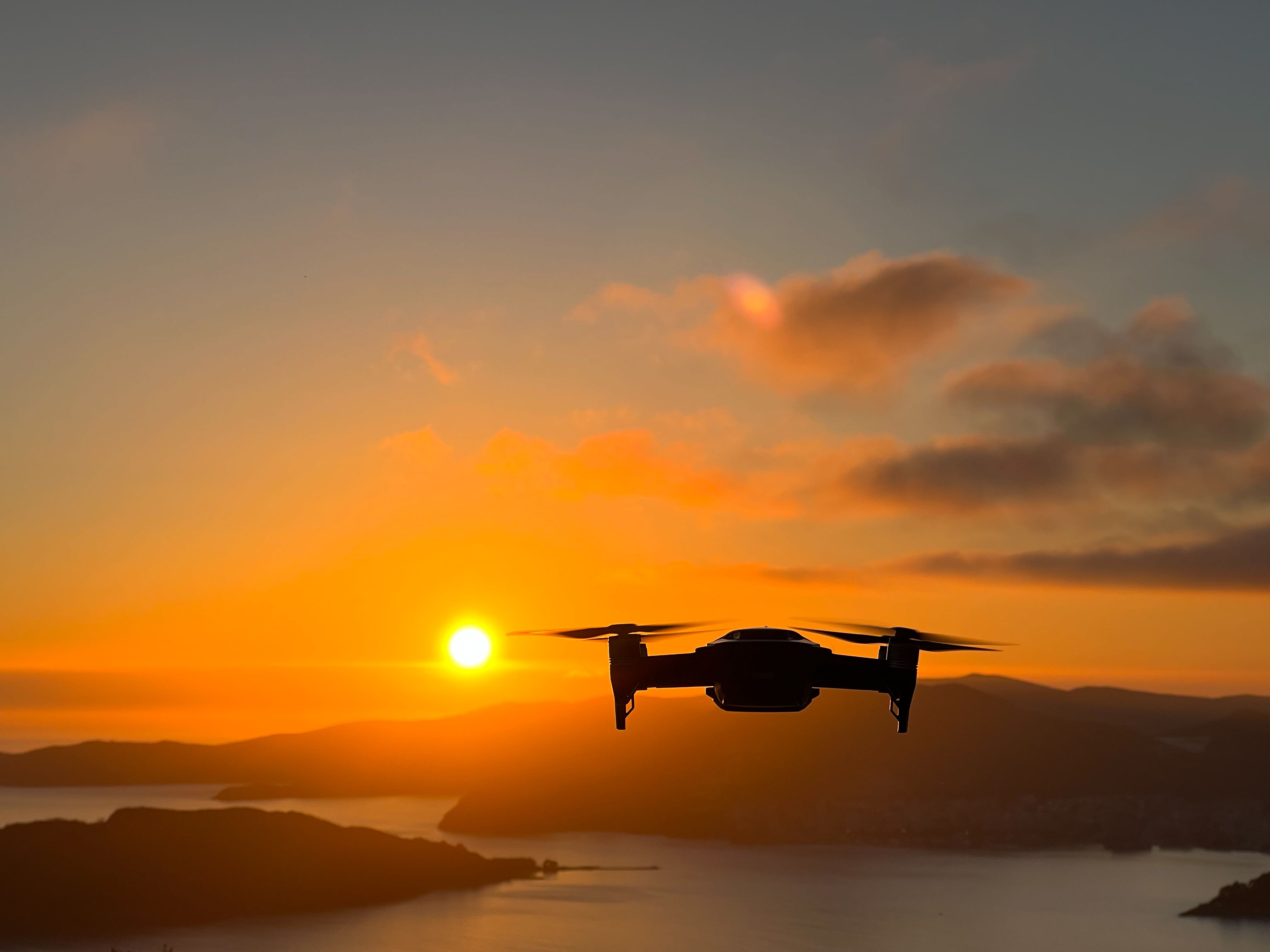 Drone filming the sea and mountains at sunset