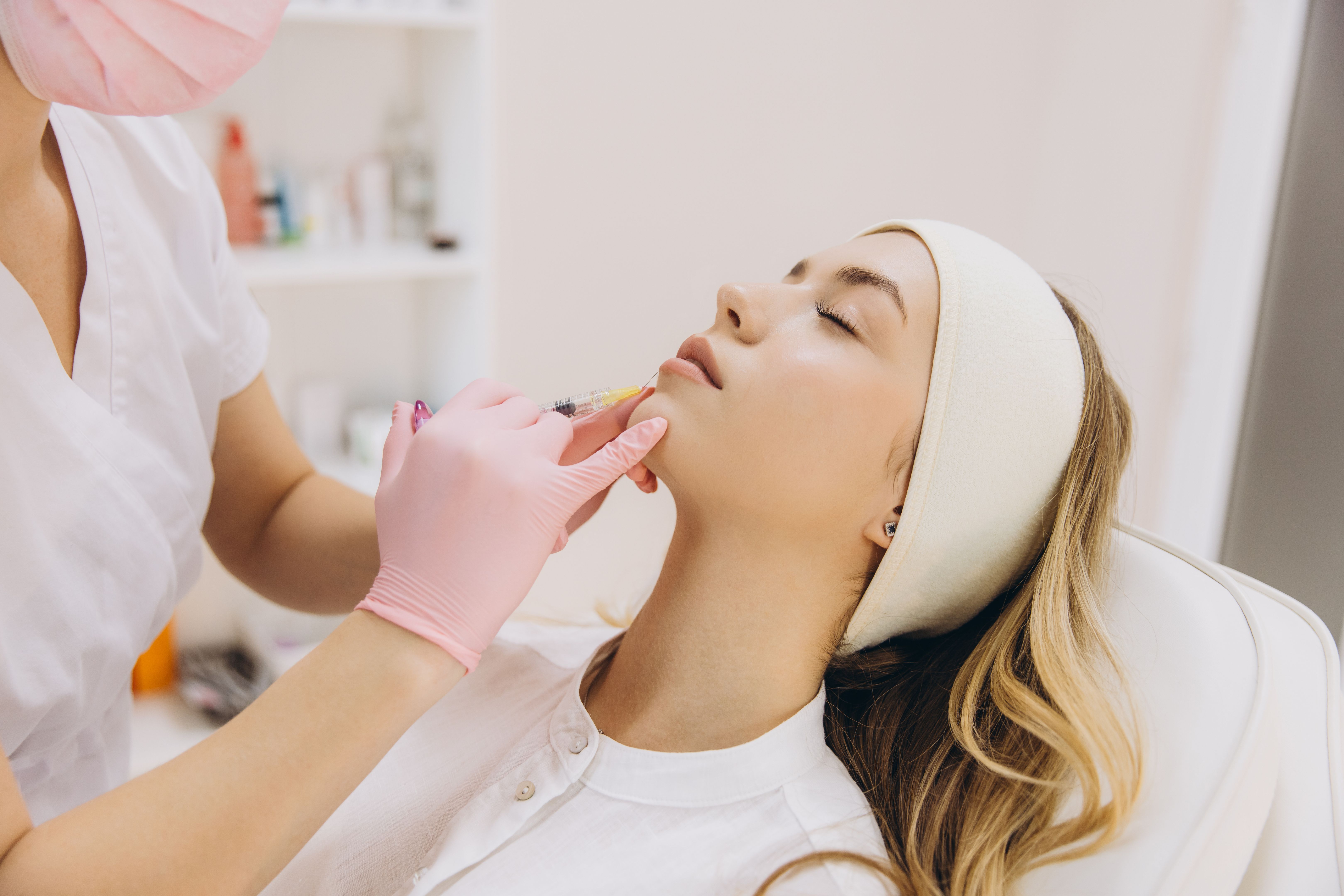 Cosmetologist performing a botox injection into a woman's lips at an aesthetic medicine clinic, enhancing beauty and rejuvenating skin