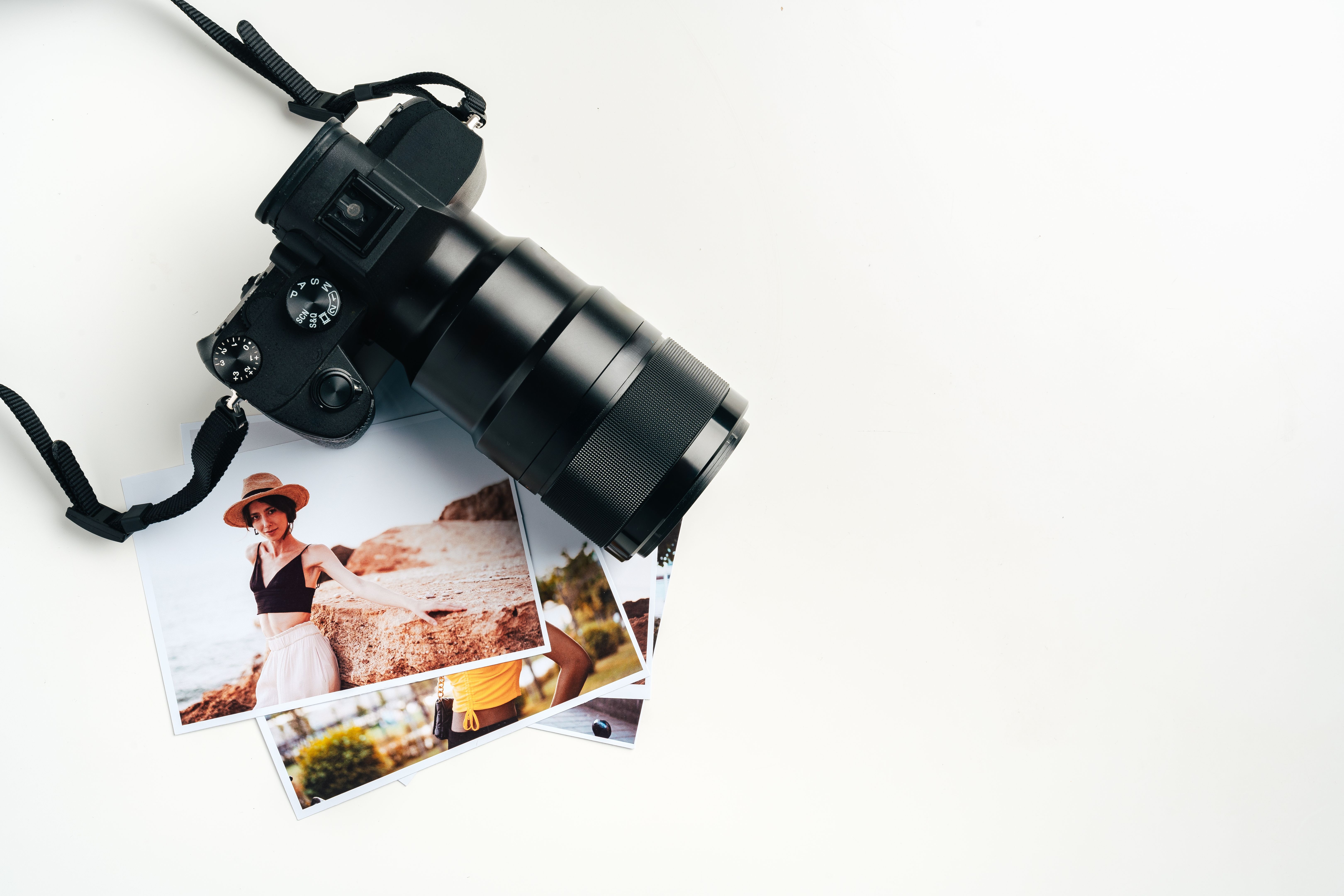 Camera and colorful printed photos of women on desk close up