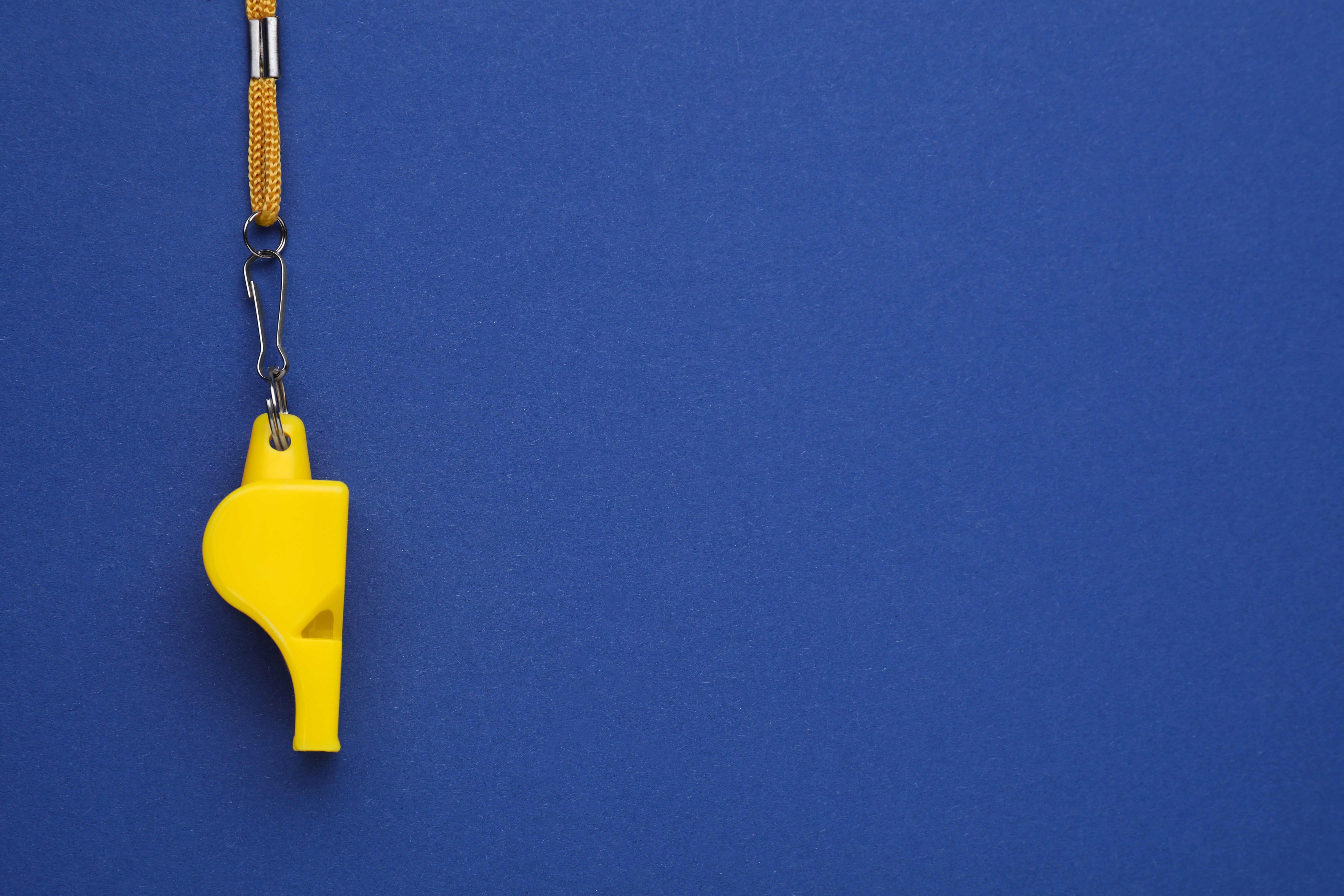 One yellow whistle with cord on blue background, top view. Space for text One yellow whistle with cord on blue background, top view. Space for text