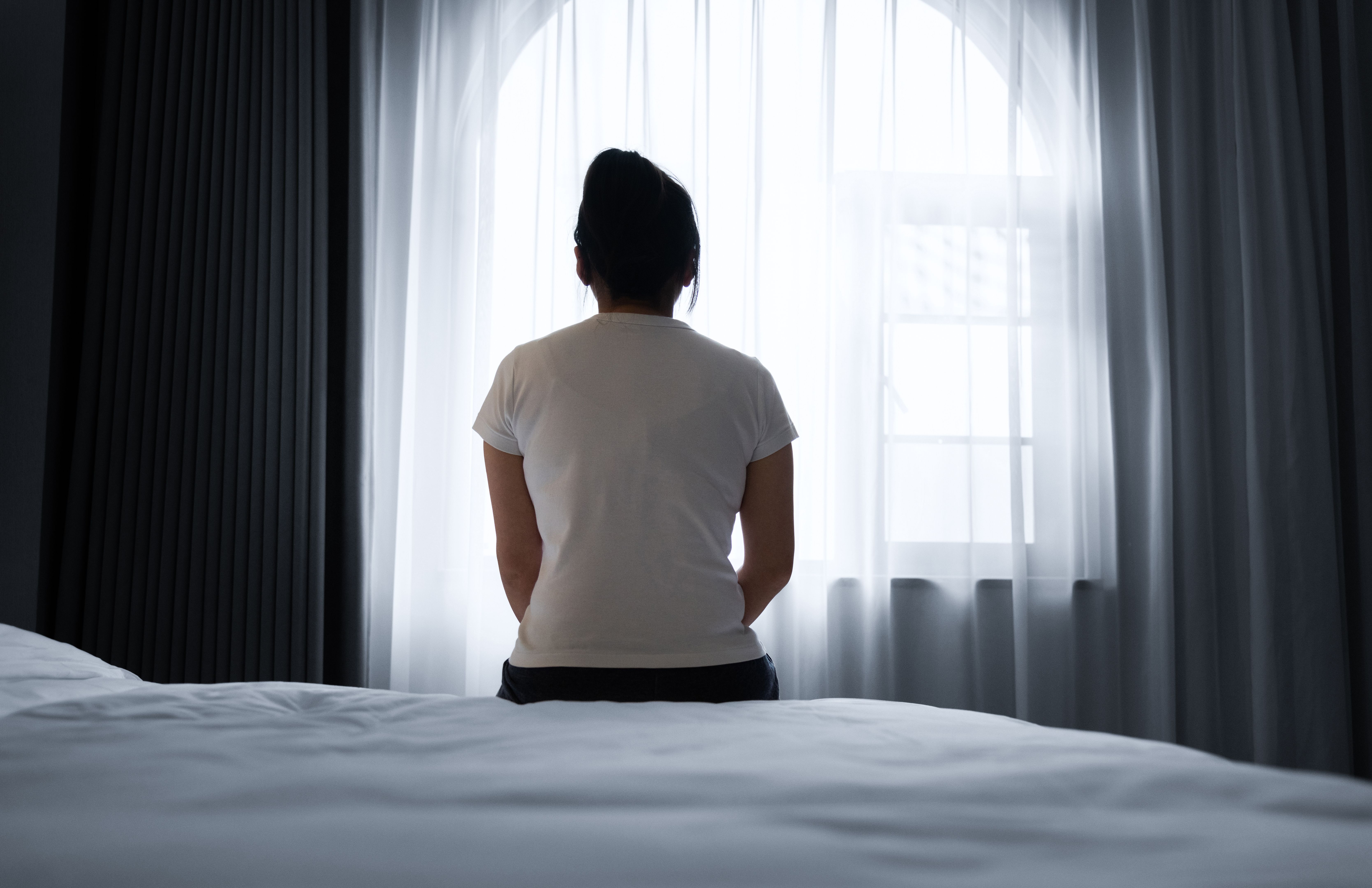 Rear view of a woman sitting on bed