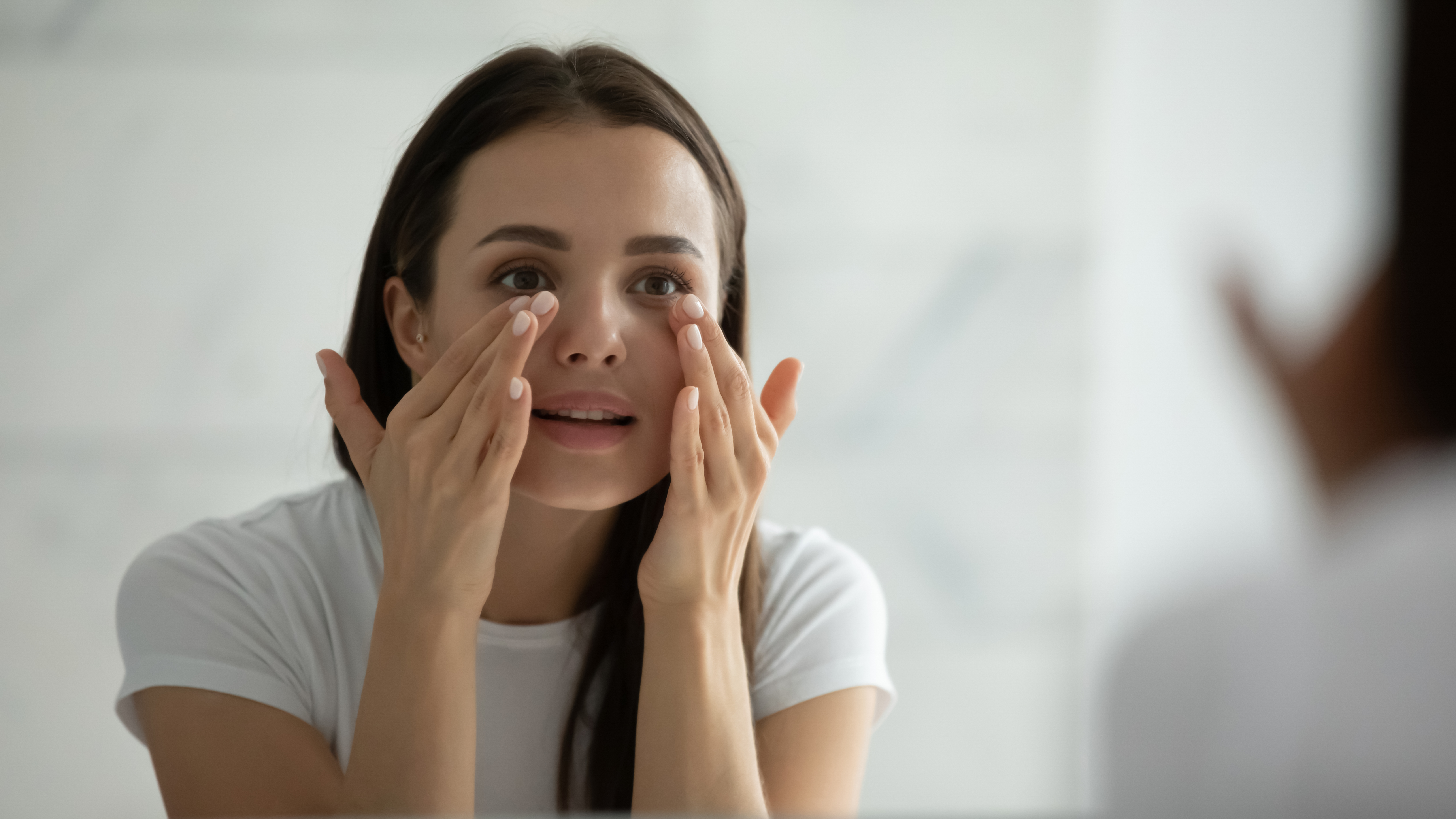 Close up smiling young woman doing facial massage, applying cream