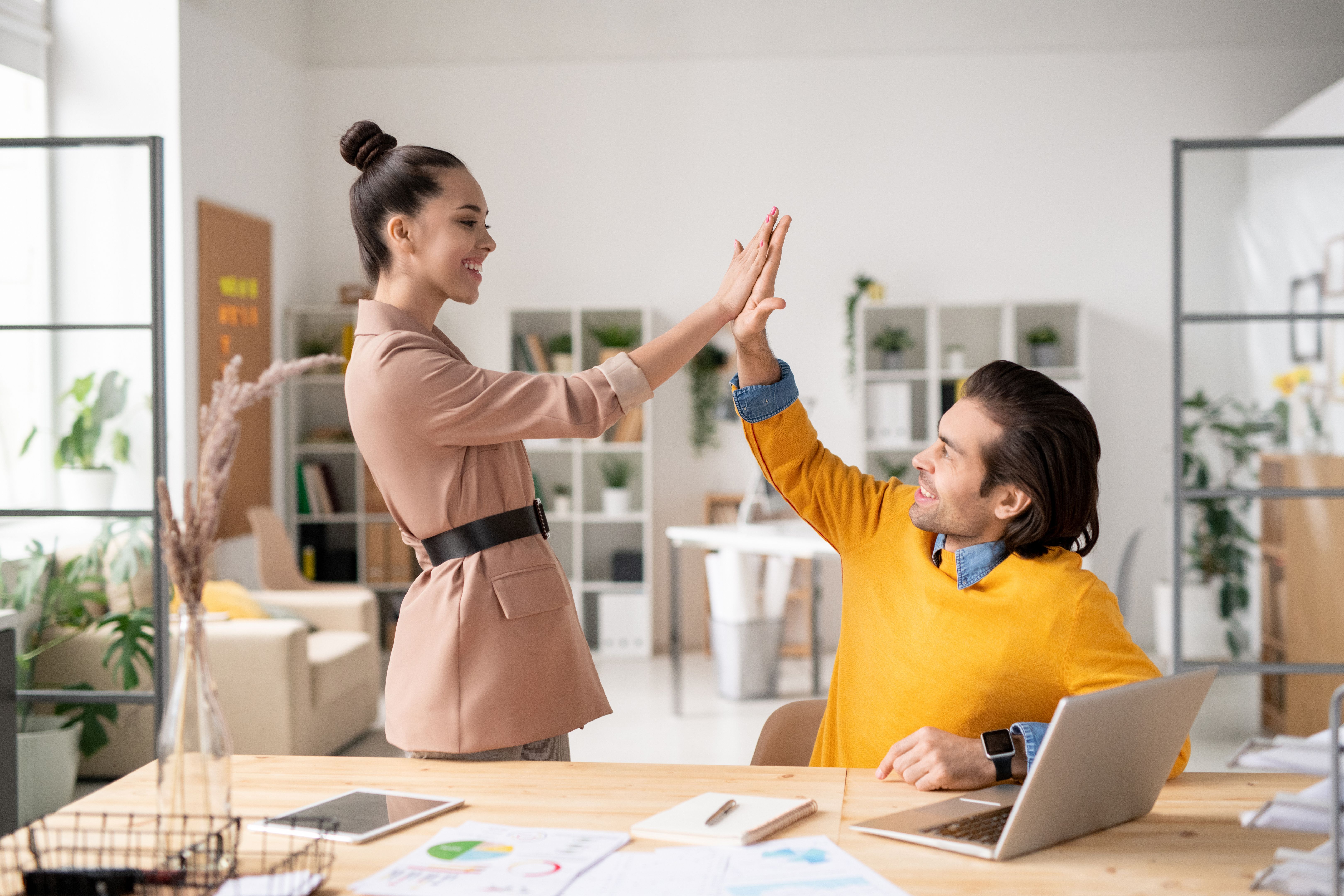 Two happy young successful colleagues giving each other high five Two happy young successful colleagues giving each other high five