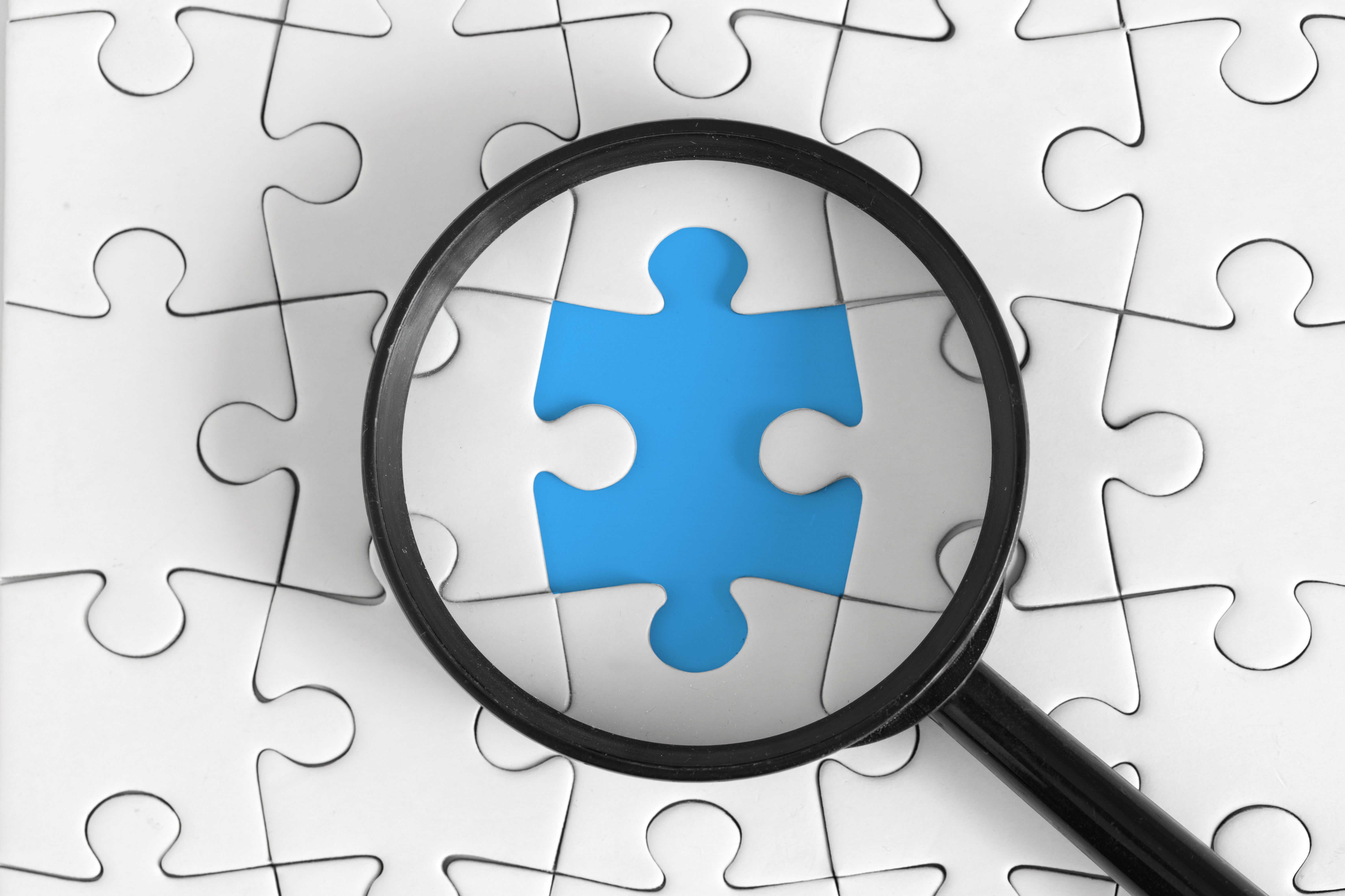 Magnifying Glass Highlights Missing Puzzle Piece on Blue Background