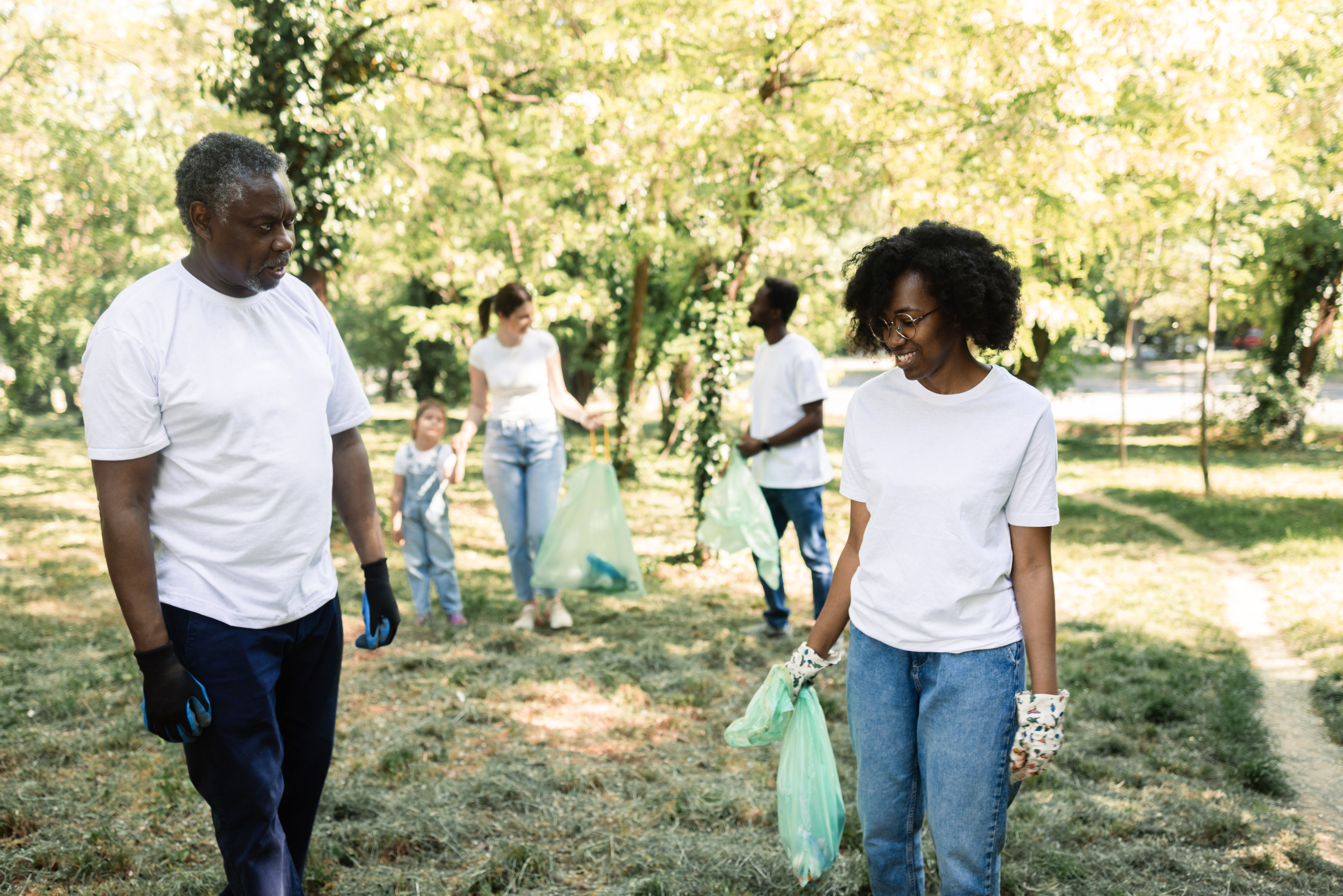African American senior man and young woman collecting garbage at their neighborhood