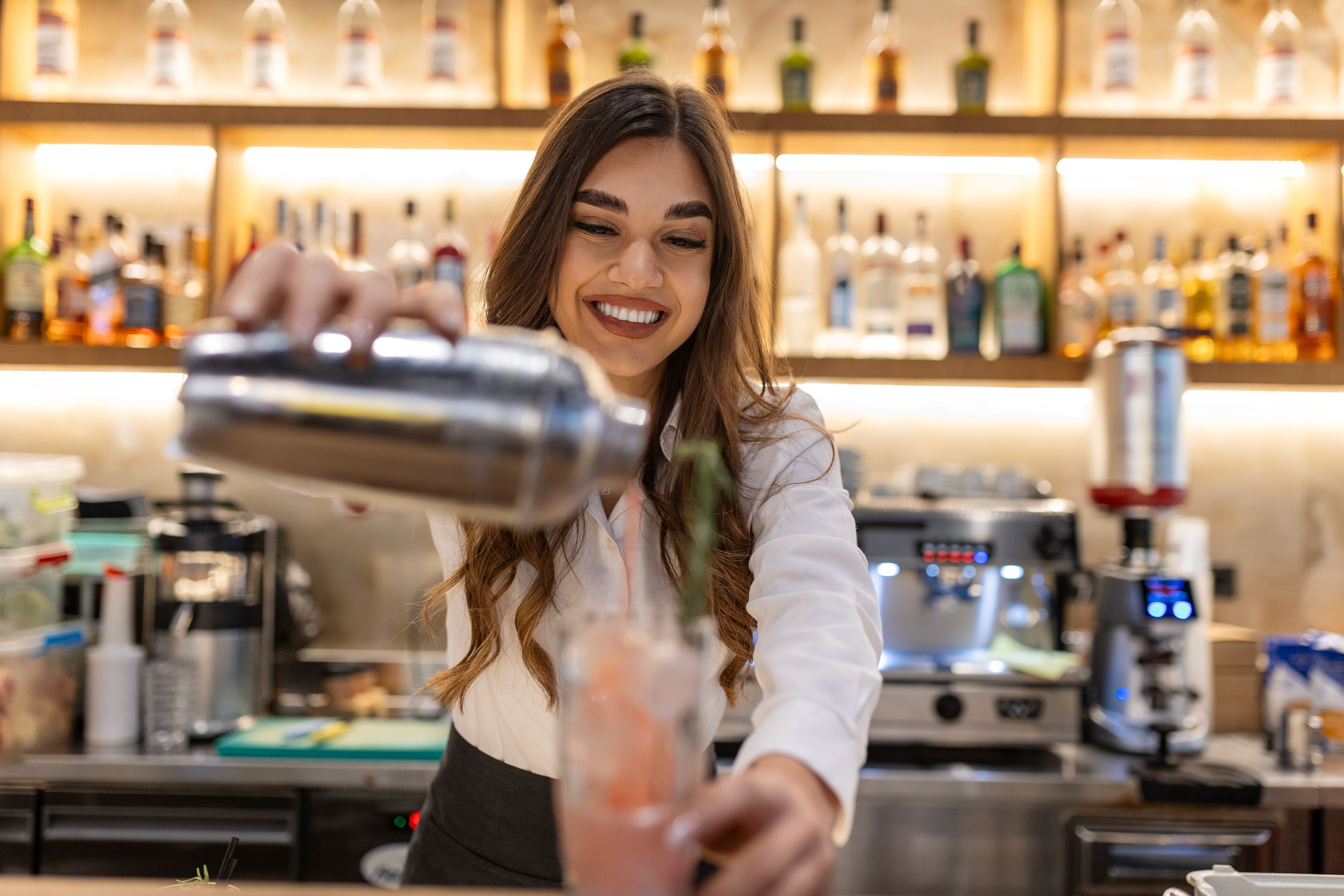 Female bartender making alcoholic cocktail on the bar counter, Young professional bartender working on a bar preparing cocktails