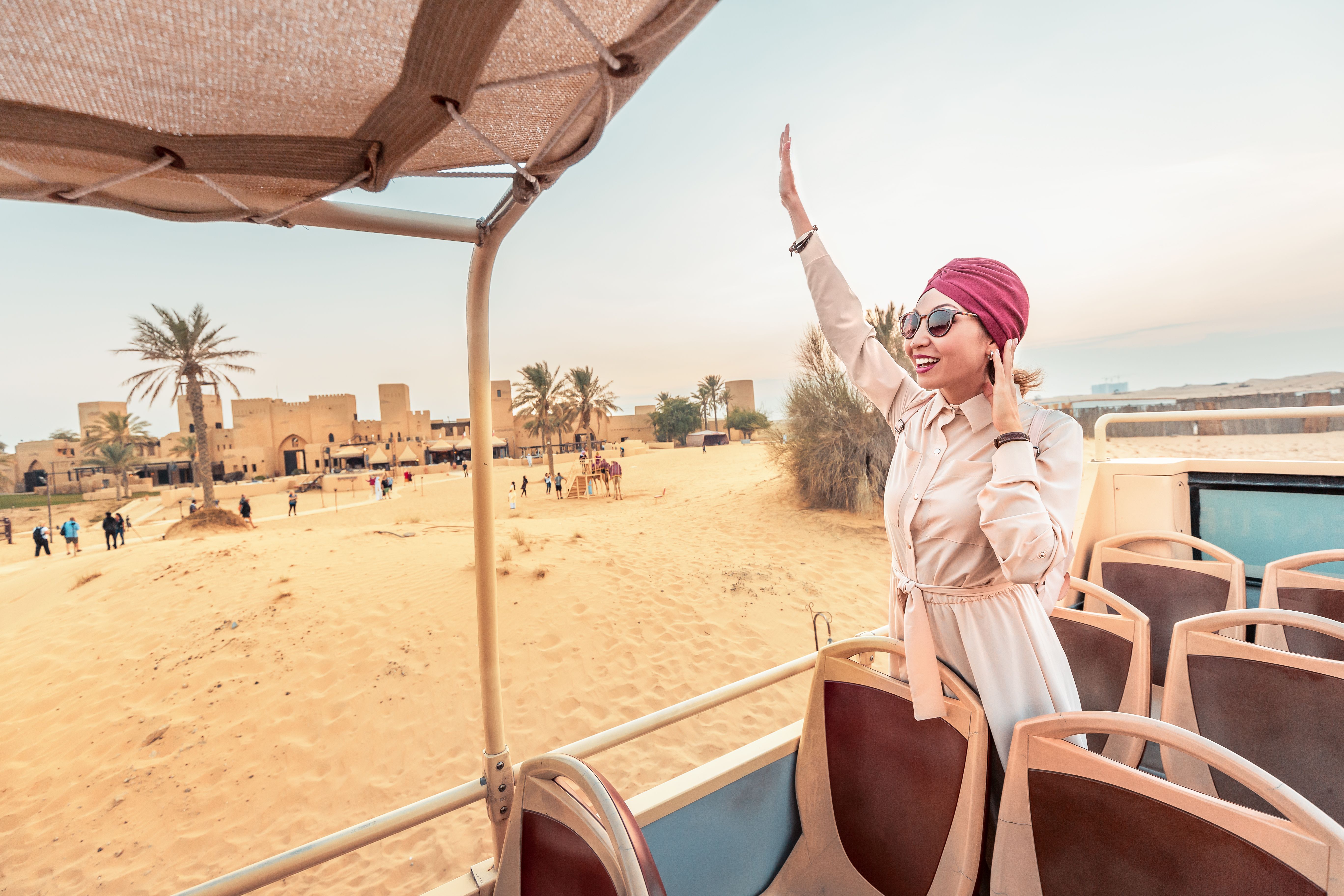 A happy girl in an Indian headdress travels on the roof of a bus in a natural and historical Park. Desert Safari and adventure concept